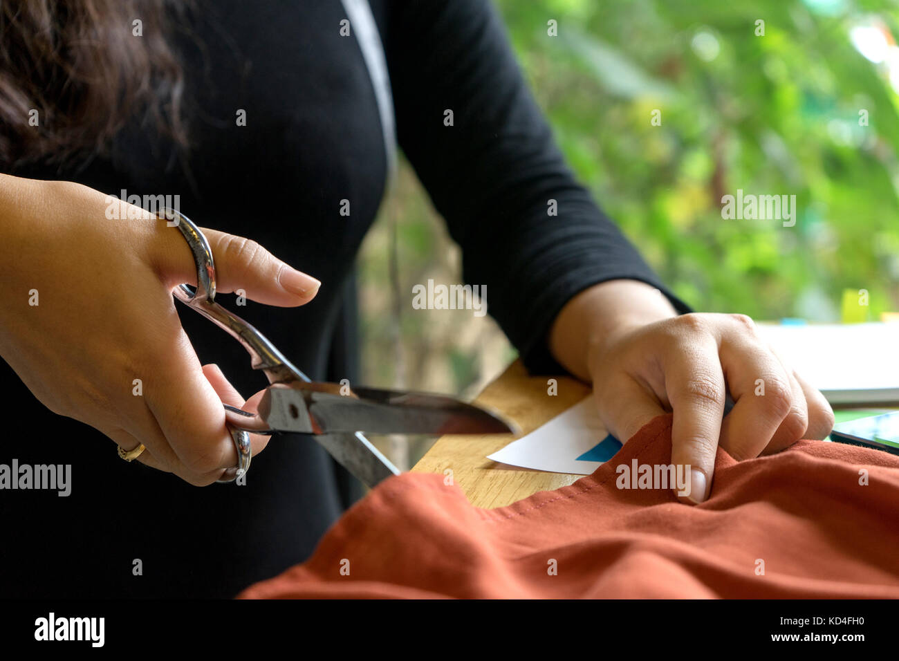 Jeune créateur de mode de travail avec chiffon de tissu sur la table en bois près de la porte de l'arbre vert Banque D'Images