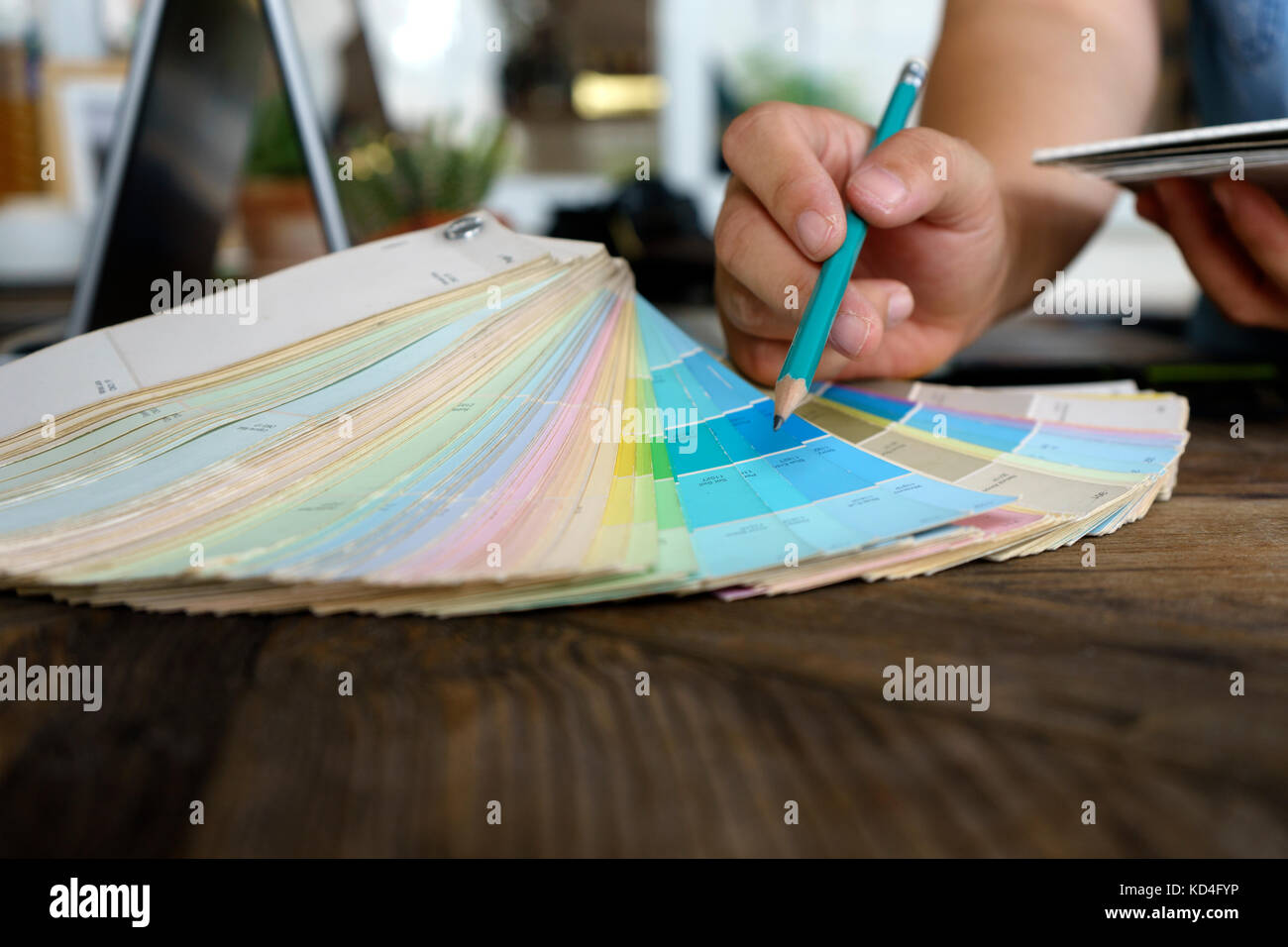 Graphic Designer travaillant avec l'ordinateur et la couleur du papier pour choisir la meilleure couleur pour le projet sur la table en bois Banque D'Images