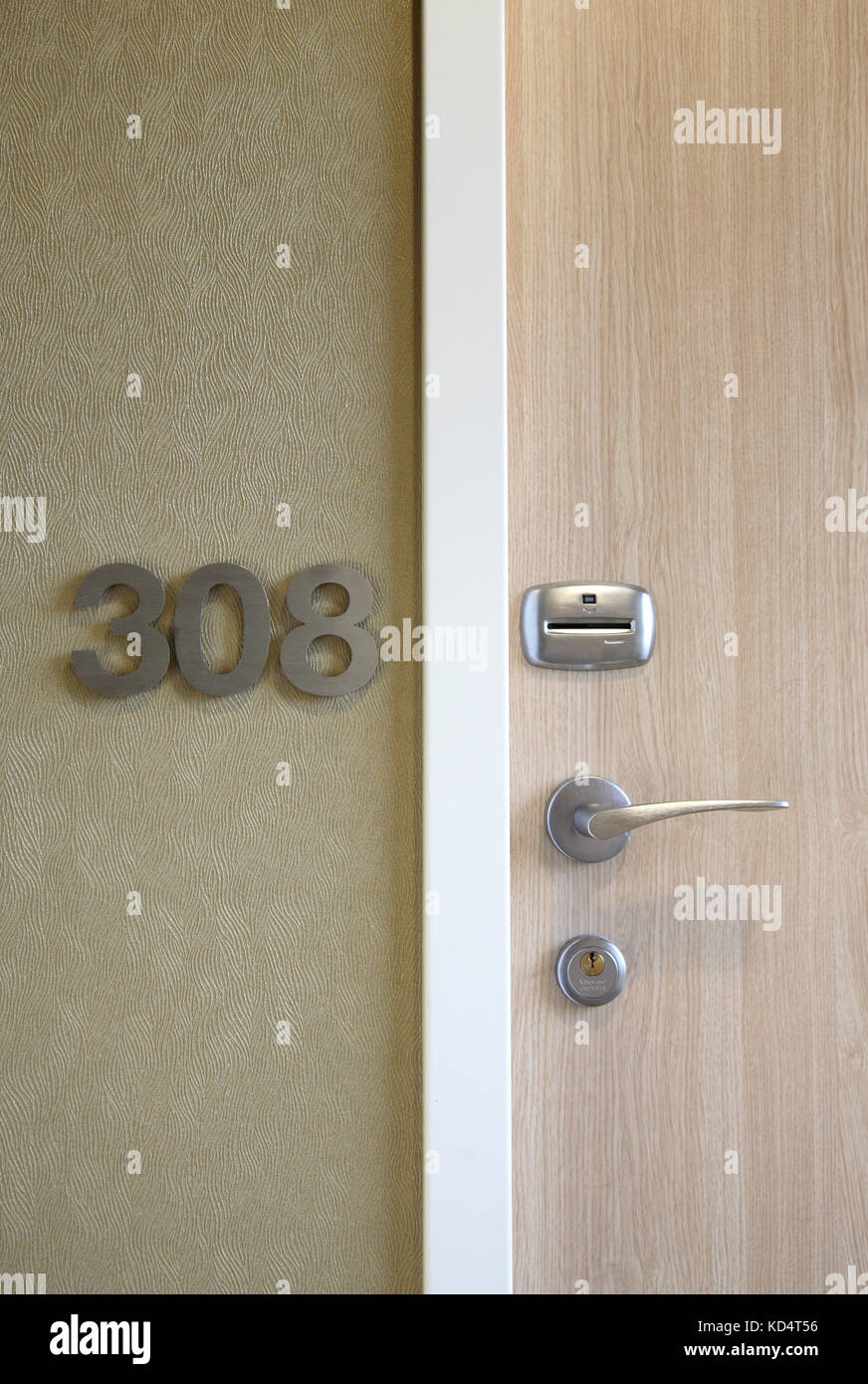 Vue rapprochée d'une porte d'hôtel moderne avec numéro de chambre en aluminium fixé au mur et serrure à carte Banque D'Images