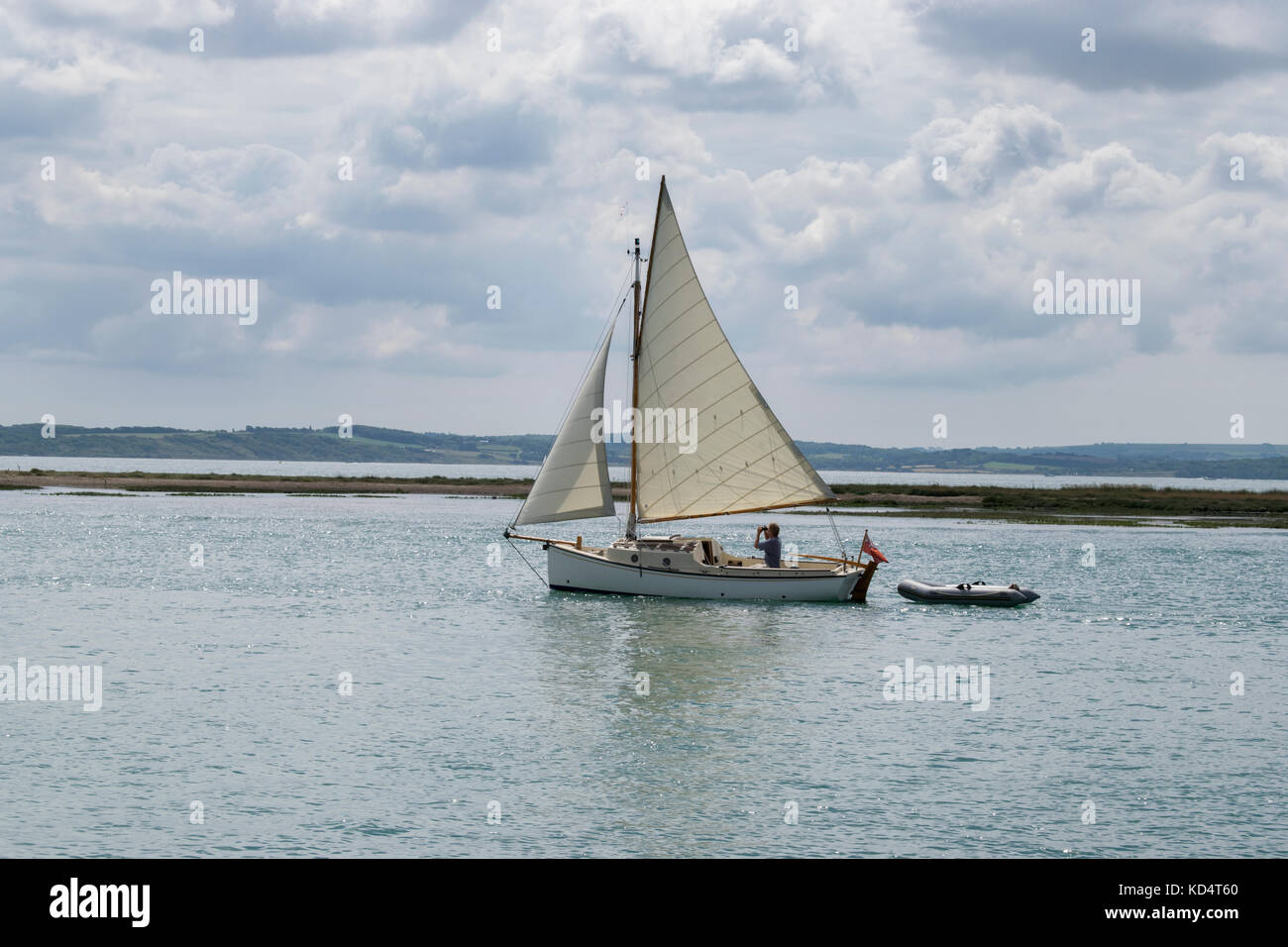 Un marin utilise des jumelles sur un yacht classique Navigation dans la rivière Beaulieu, Beaulieu avec Spit et le Solent dans l'arrière-plan Banque D'Images