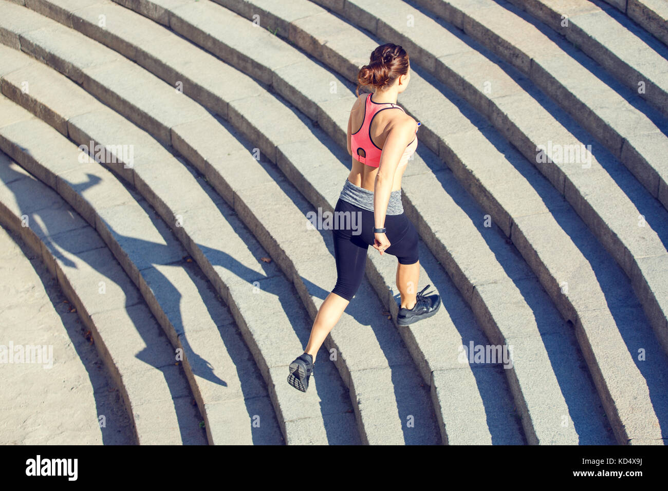 Jeune femme slim rose en haut courir vers le haut dans les escaliers le matin ville. mode de vie sain avec fond copyspace Banque D'Images