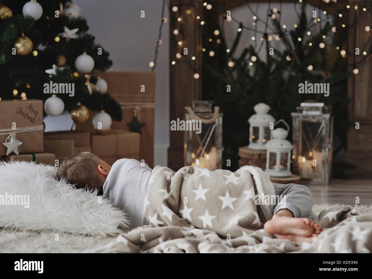 Garçon prendre une sieste à côté de l'arbre de Noël Banque D'Images