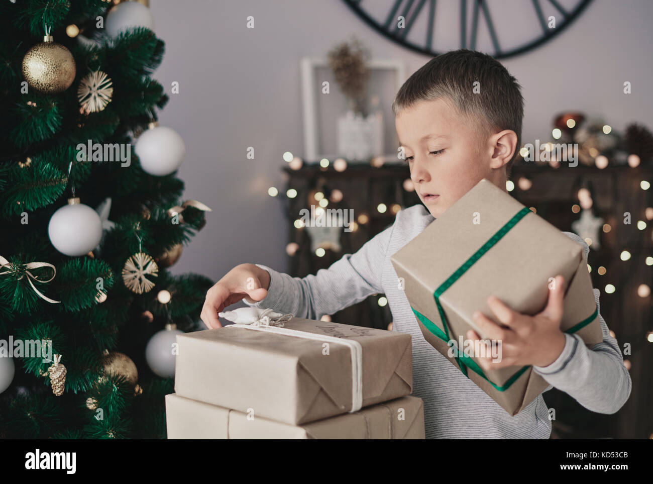 Garçon debout à côté de l'arbre de Noël et cadeaux en tenant Banque D'Images