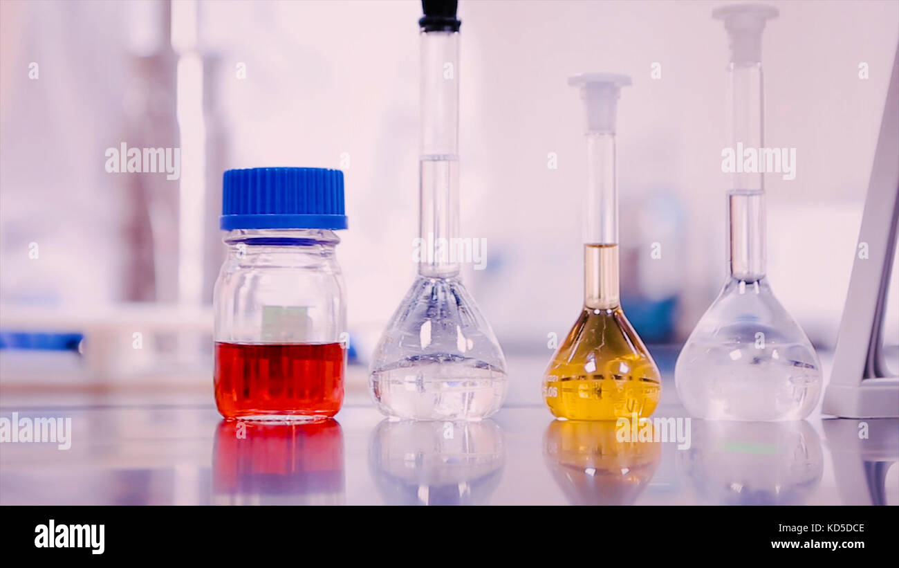 Flacons de laboratoire et gobelets avec des liquides de différentes couleurs sur table lab Banque D'Images