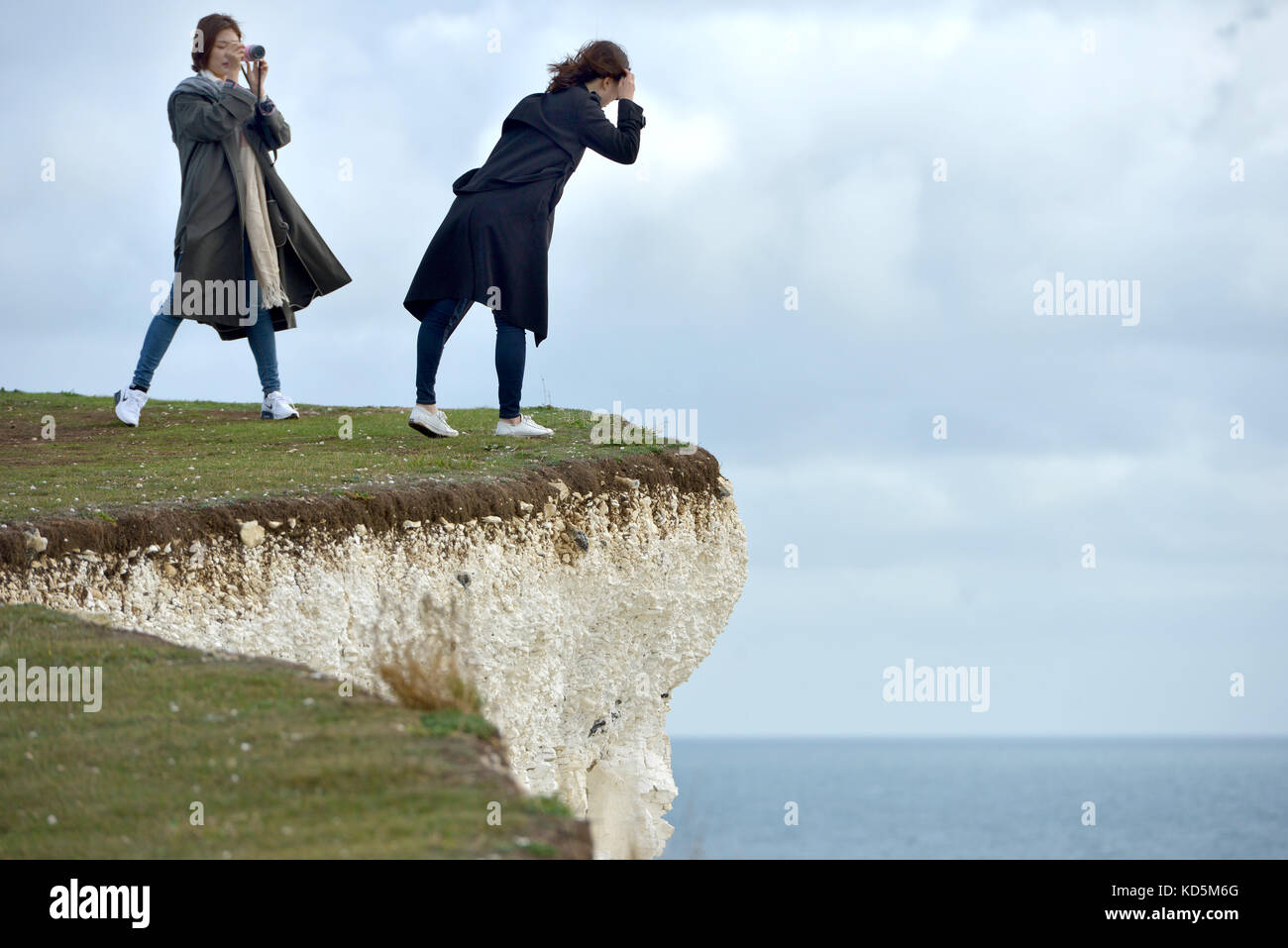 Les touristes se trouve près du bord de l'effondrement des falaises de craie à Birlng Gap, East Sussex Banque D'Images