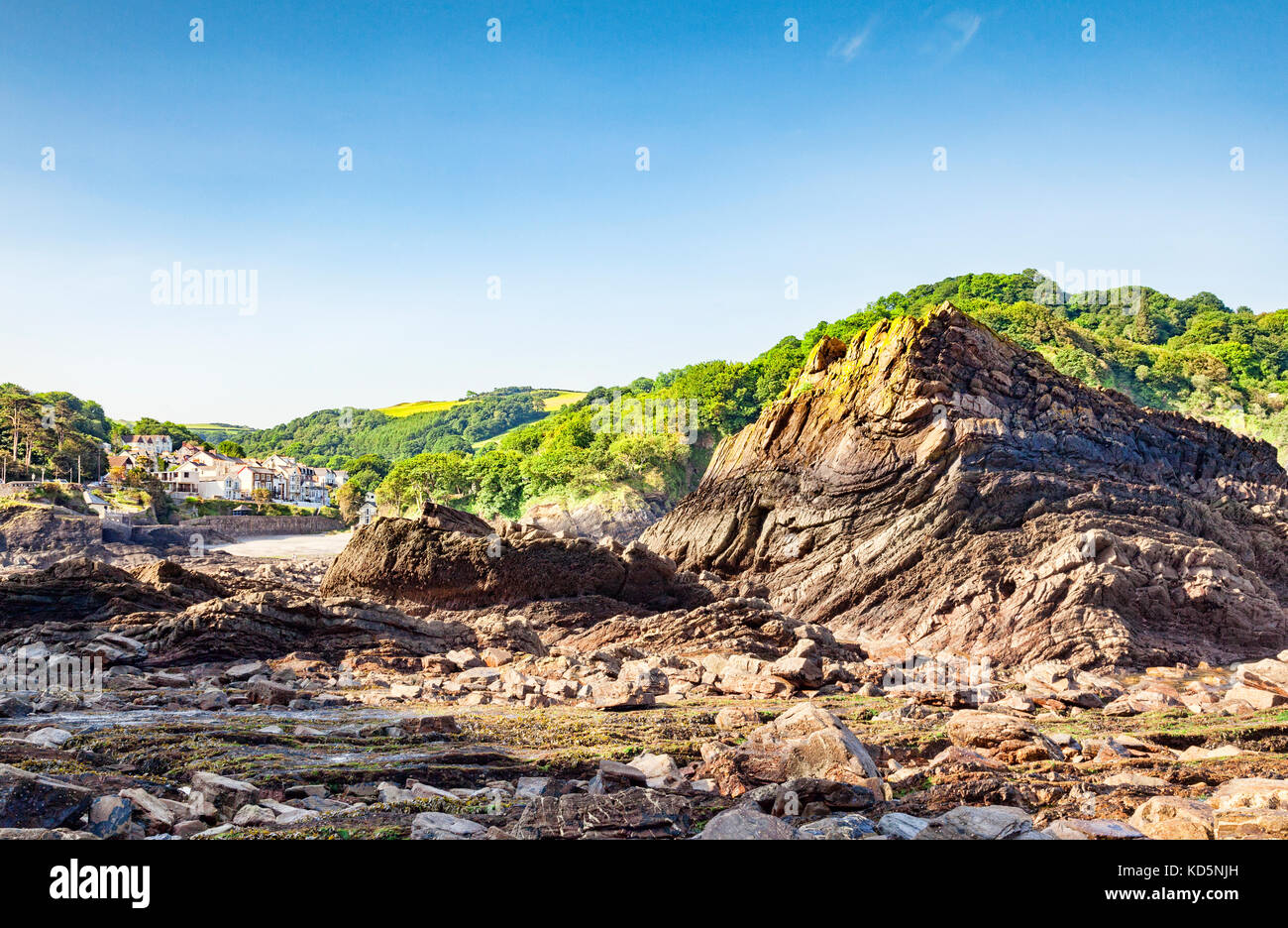 La plage rocheuse à combe martin, North Devon, Angleterre, Royaume-Uni, avec le village en arrière-plan. Banque D'Images