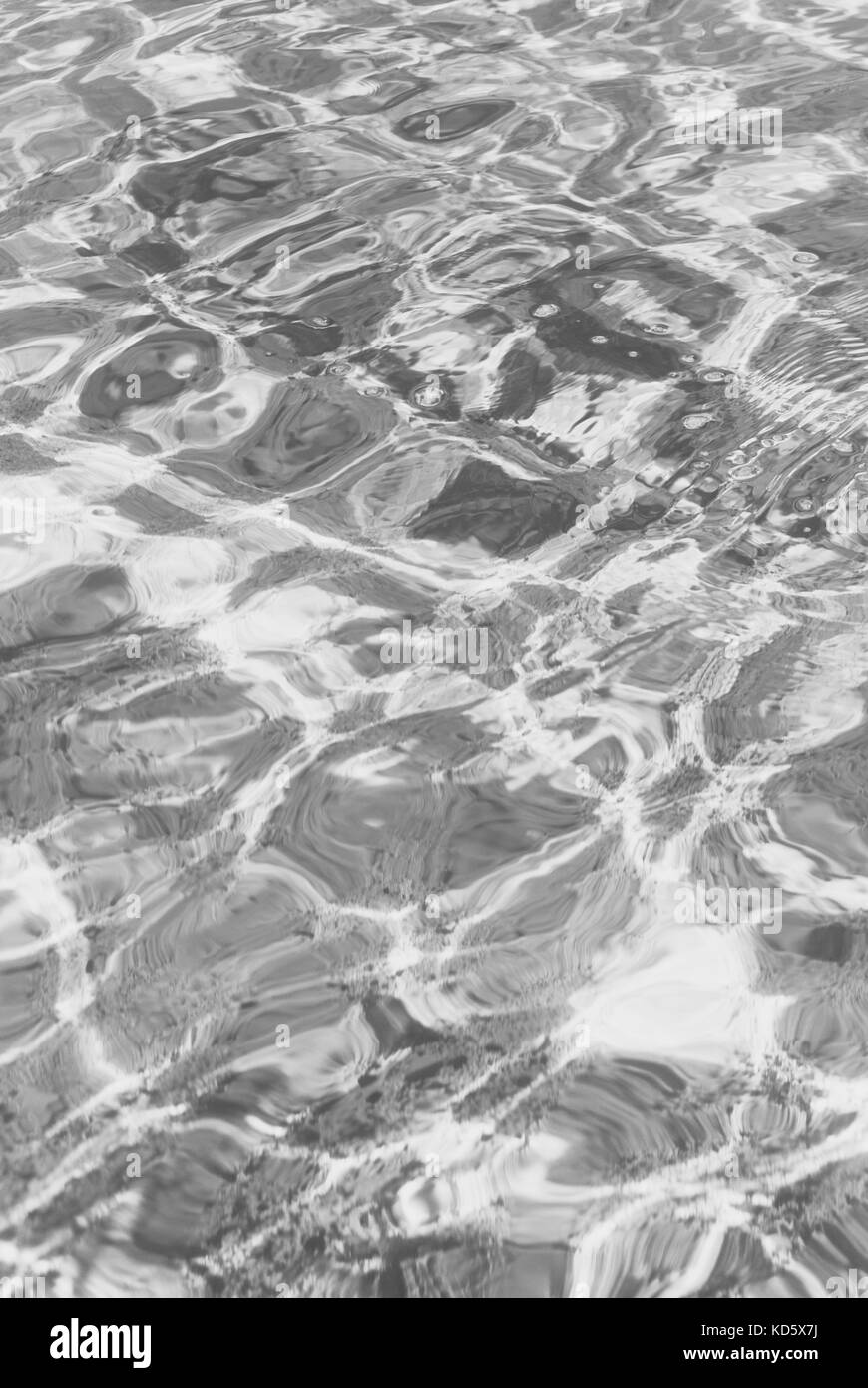 La réfraction de la lumière dans l'eau claire avec de petites vagues. photo en noir et blanc Banque D'Images