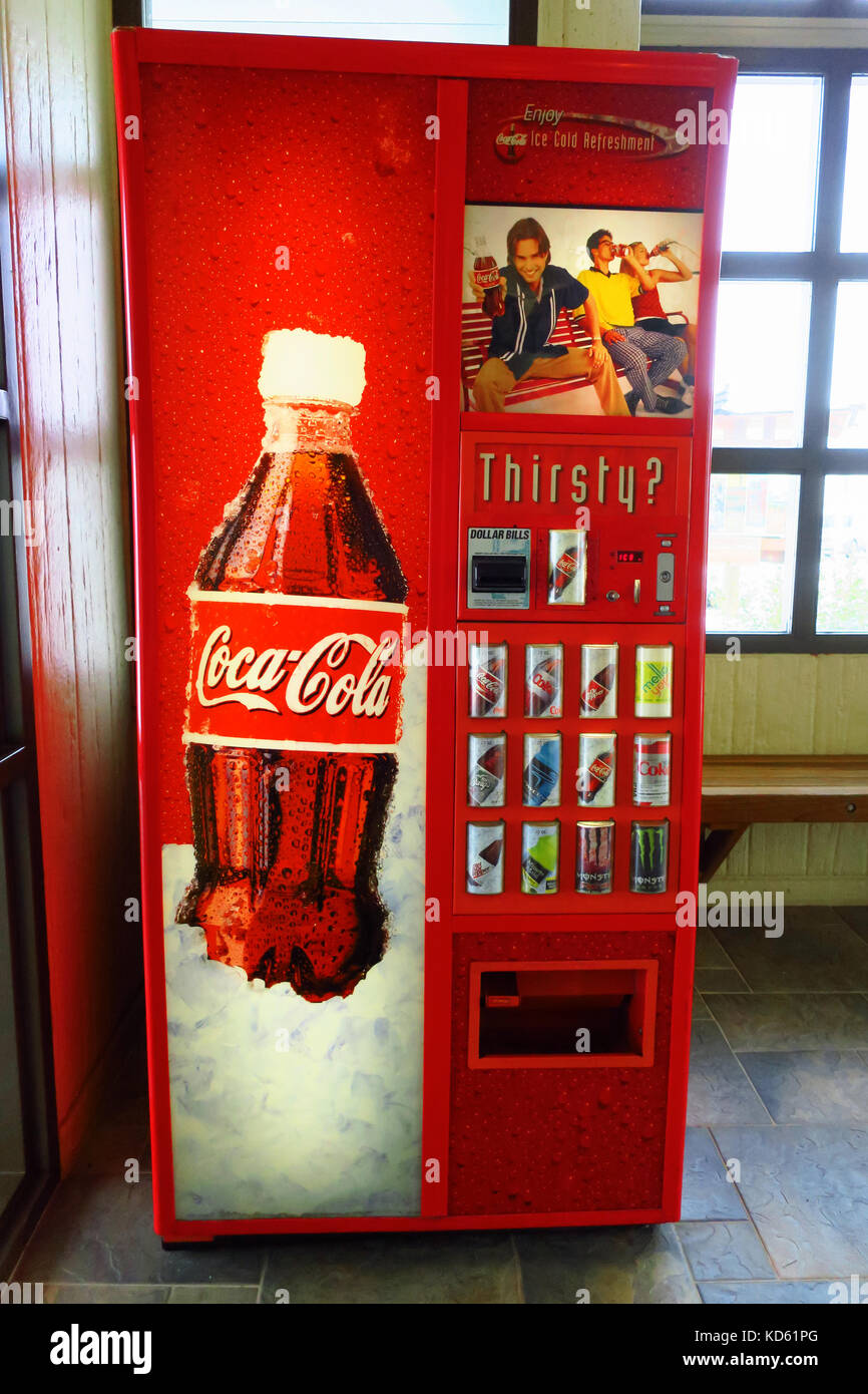 Un homme mettant l'argent dans une machine à coca cola rouge dans une zone de repos. Banque D'Images Un homme mettant l'argent dans une machine à coca cola rouge dans une zone de repos. Banque D'Images