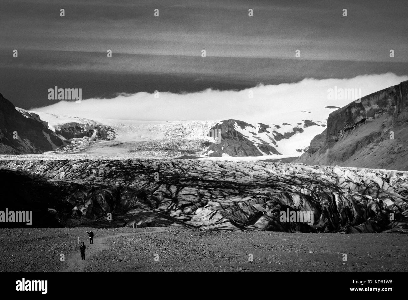 Chemin vers le glacier Skaftafellsjokull avec peu de personnes méconnues, à Skaftafell, en Islande, en été, noir et blanc avec du grain Banque D'Images