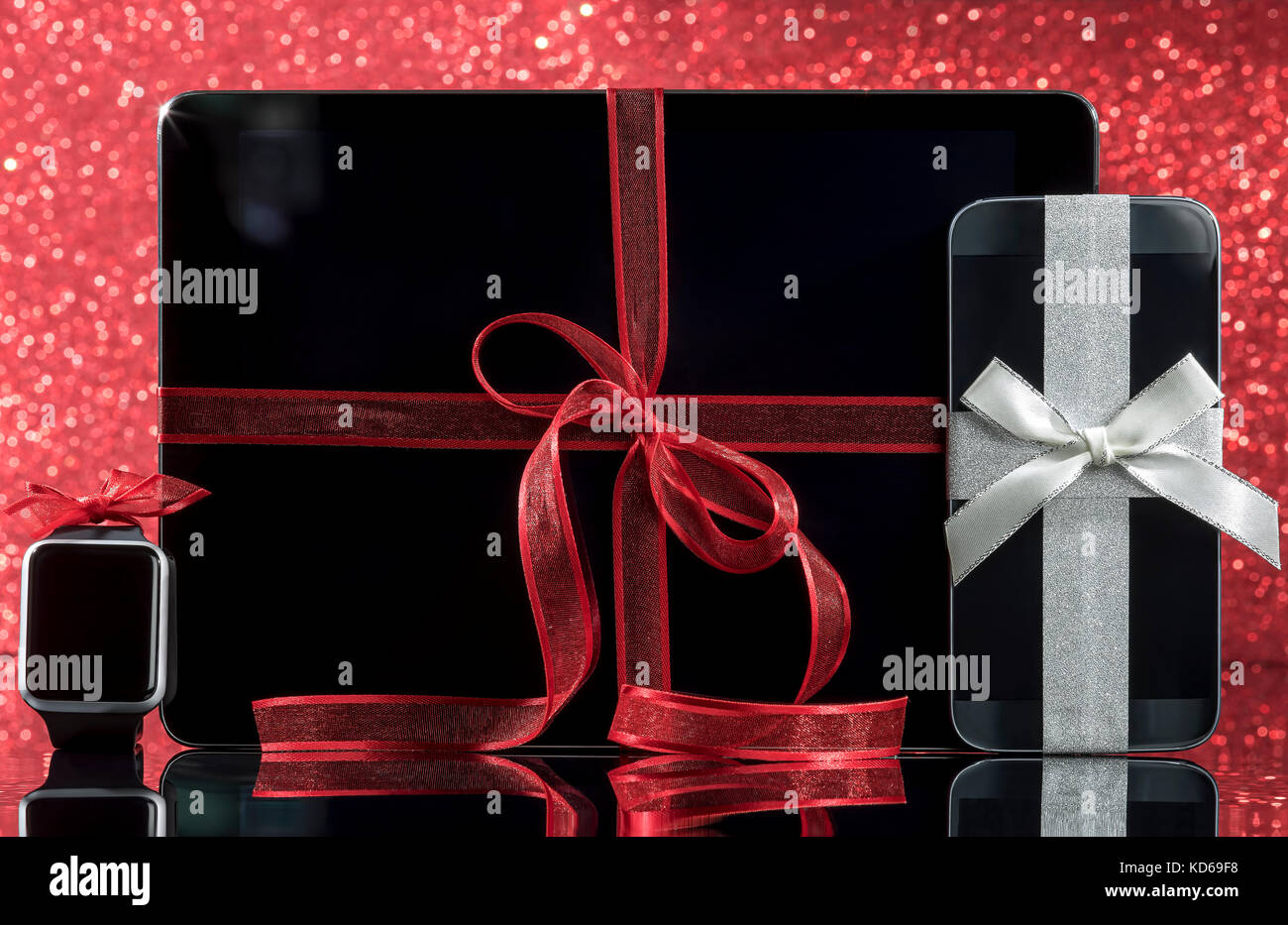 Smartwatch et smartphone et PC tablette et décorations pour arbre de Noël sur la table en verre noir sur fond rouge. L'accent sur smartphone. Banque D'Images