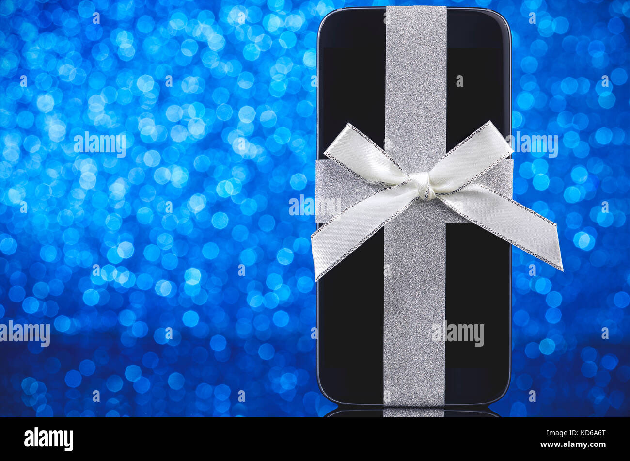 Smartphone pour arbre de Noël sur la table en verre noir sur fond bleu. L'accent sur smartphone. Banque D'Images