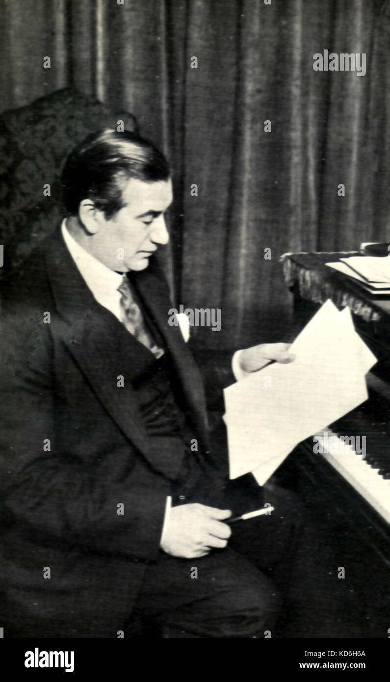 Albert Coates, chef d'orchestre, assis par piano à au score avec porte-cigarette dans la main. 1882-1953. Banque D'Images