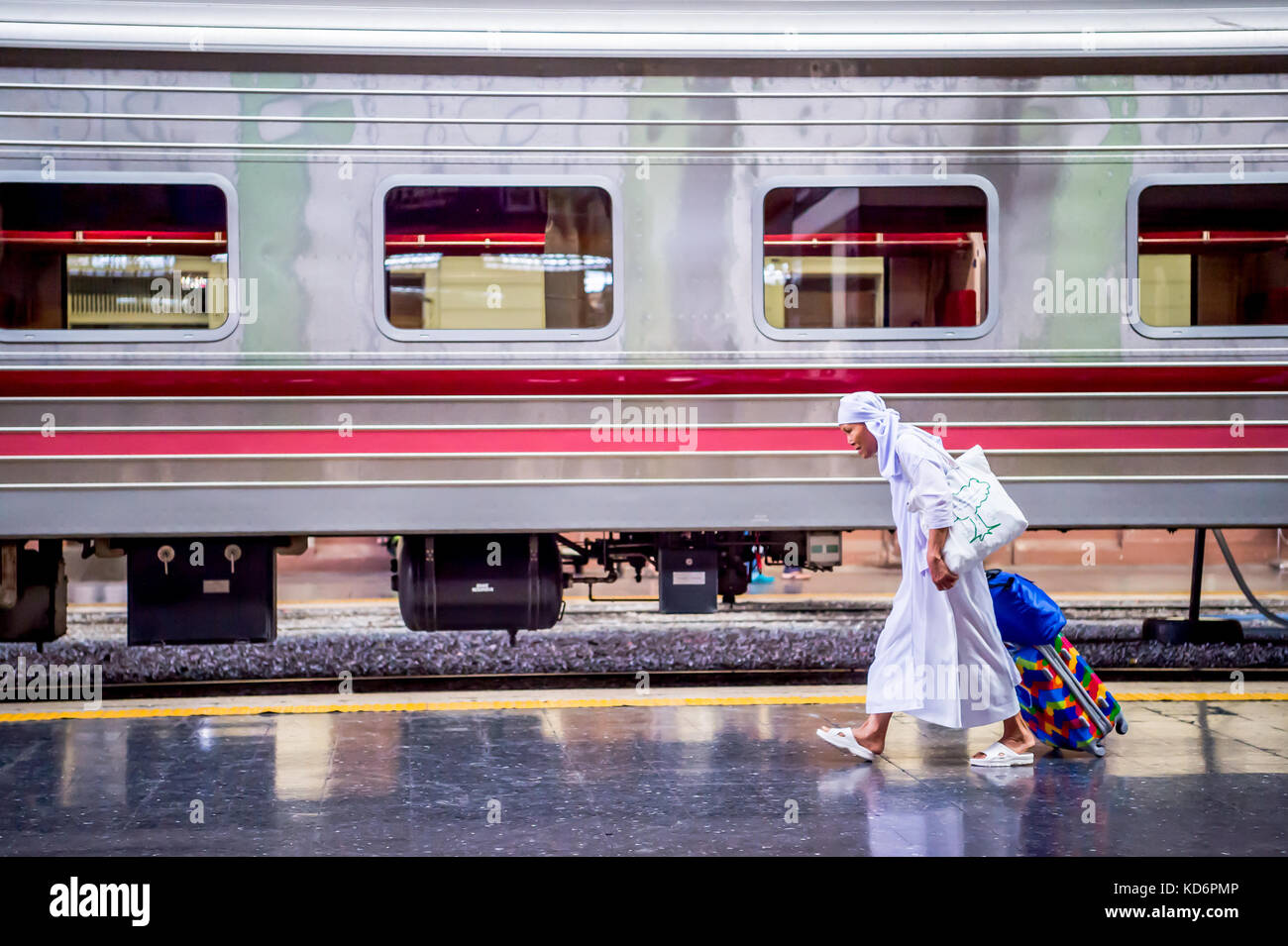 Une nonne bouddhiste thaï fait son chemin à travers la plate-forme du train transportant des bagages à la gare de hua lamphong dans le centre de Bangkok en Thaïlande en Asie. Banque D'Images