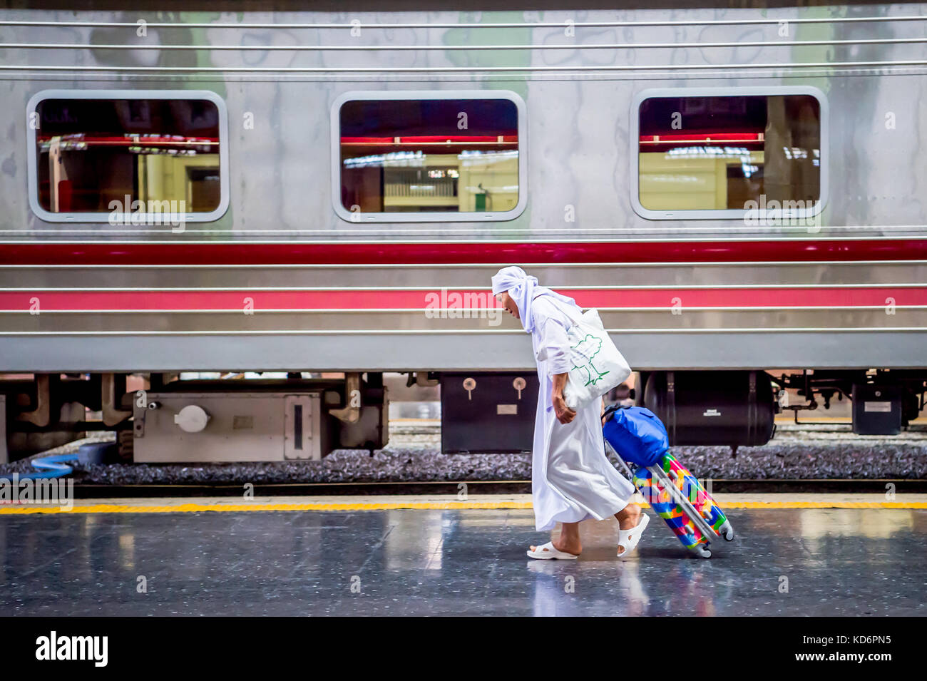 Une nonne bouddhiste thaï fait son chemin à travers la plate-forme du train transportant des bagages à la gare de hua lamphong dans le centre de Bangkok en Thaïlande en Asie. Banque D'Images