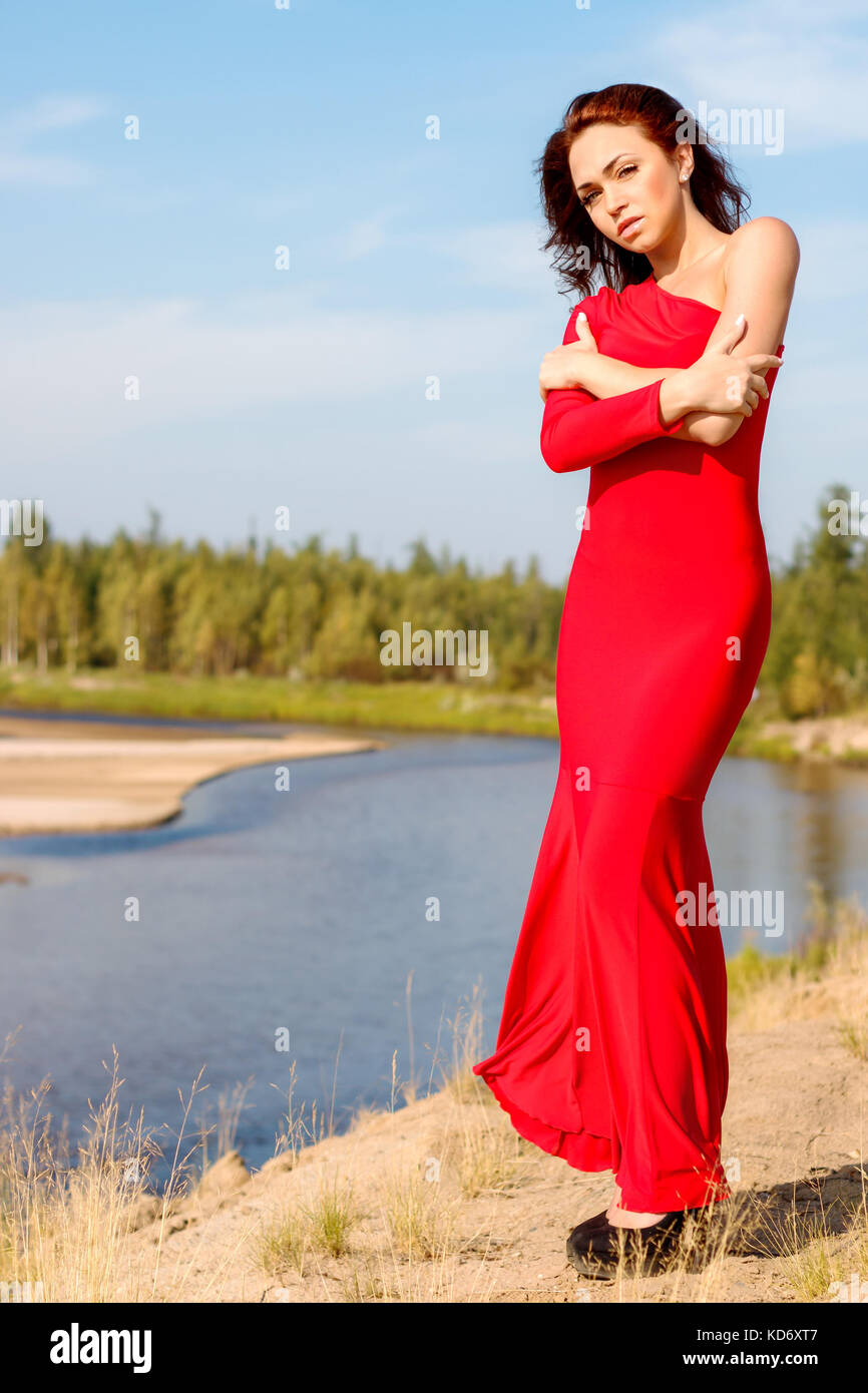 Dame dans une robe rouge restant sur le bord de la rivière Banque D'Images