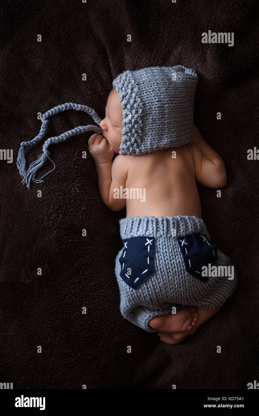 Bébé nouveau-né dans un costume en tricot gris dort dans un beau poser Banque D'Images