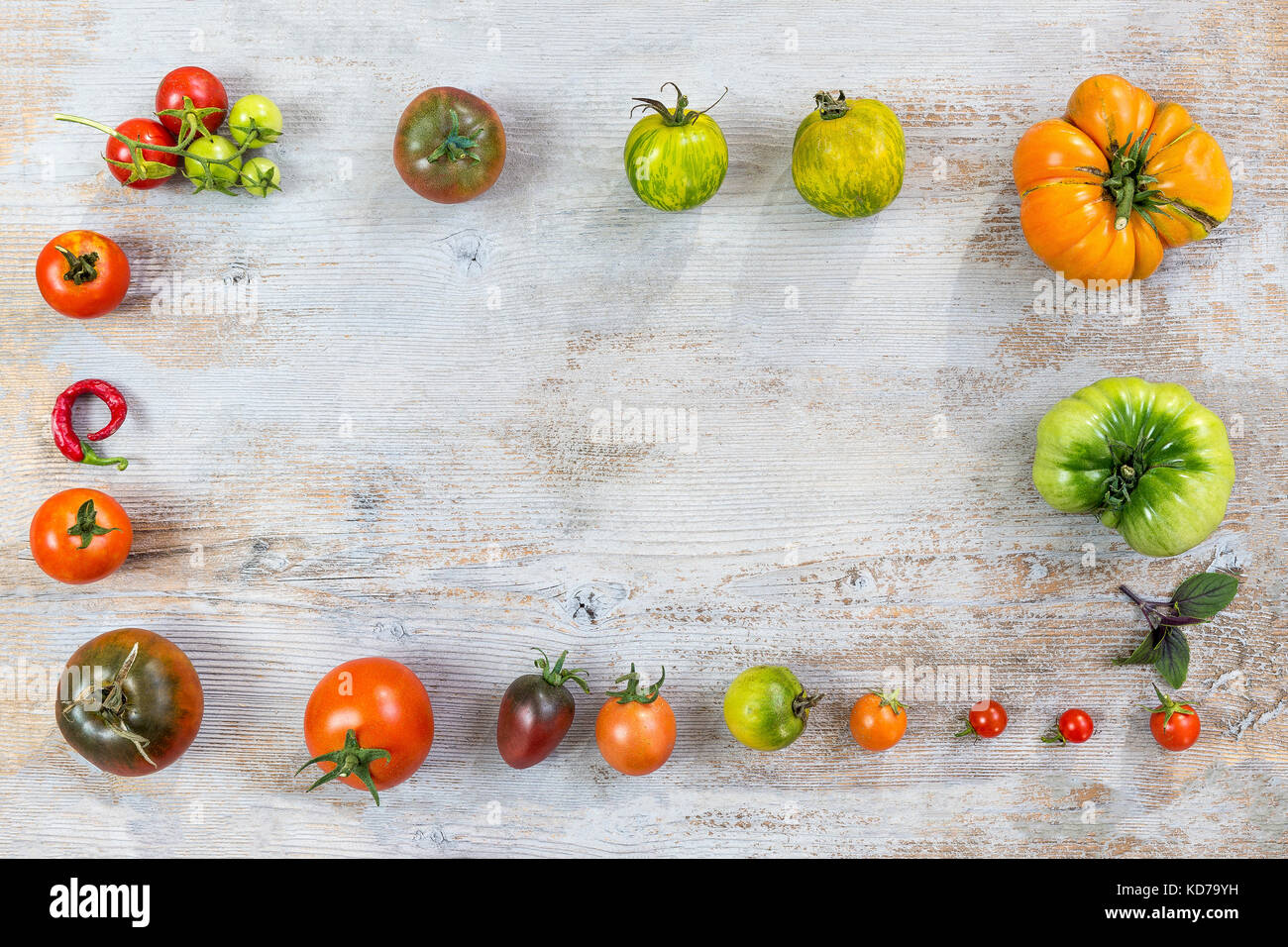 Châssis de différentes matières organiques couleur homegrown tomatoes on ancienne en bois peint en arrière-plan. avec fond rouge, jaune, orange et vert les tomates. La nourriture végétarienne saine concept. copie espace. Vue de dessus Banque D'Images