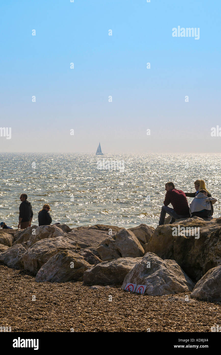 Les gens plage mer, vue de jour-voyageurs à Felixstowe plage assis sur une groyne et regardant la mer un après-midi d'été, Suffolk, Angleterre, Royaume-Uni. Banque D'Images