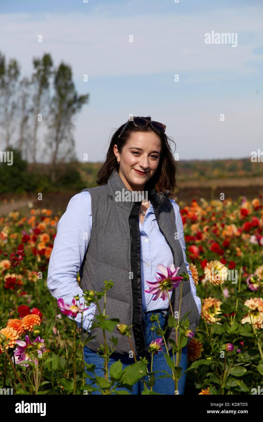 Portrait of a young woman smiling dans un champ de dahlias en automne Banque D'Images