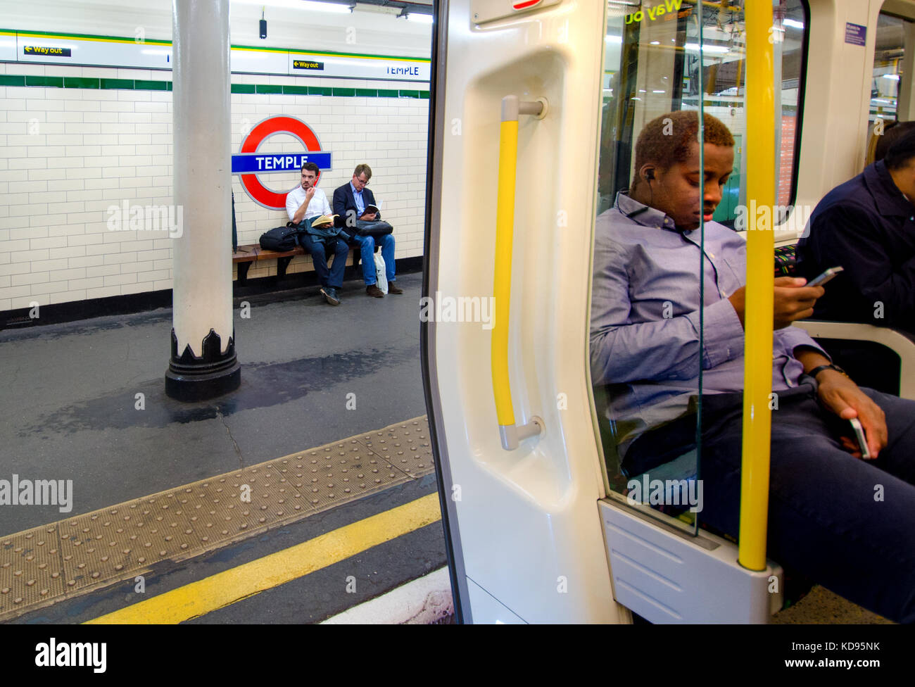 Londres, Angleterre, Royaume-Uni. La station de métro Temple - hommes sur la lecture de la plate-forme Banque D'Images
