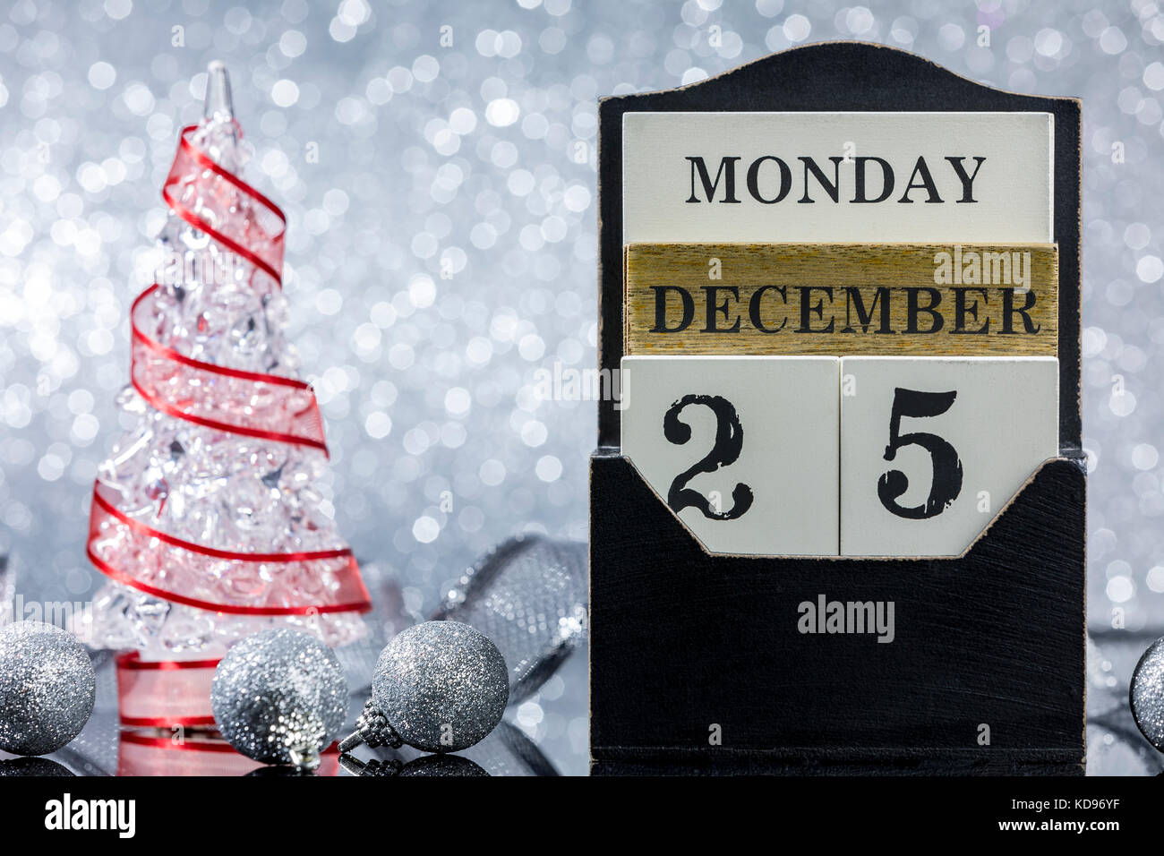 Ornements de Noël avec le calendrier et l'arbre de Noël la réflexion sur une table en verre sur fond argenté Banque D'Images