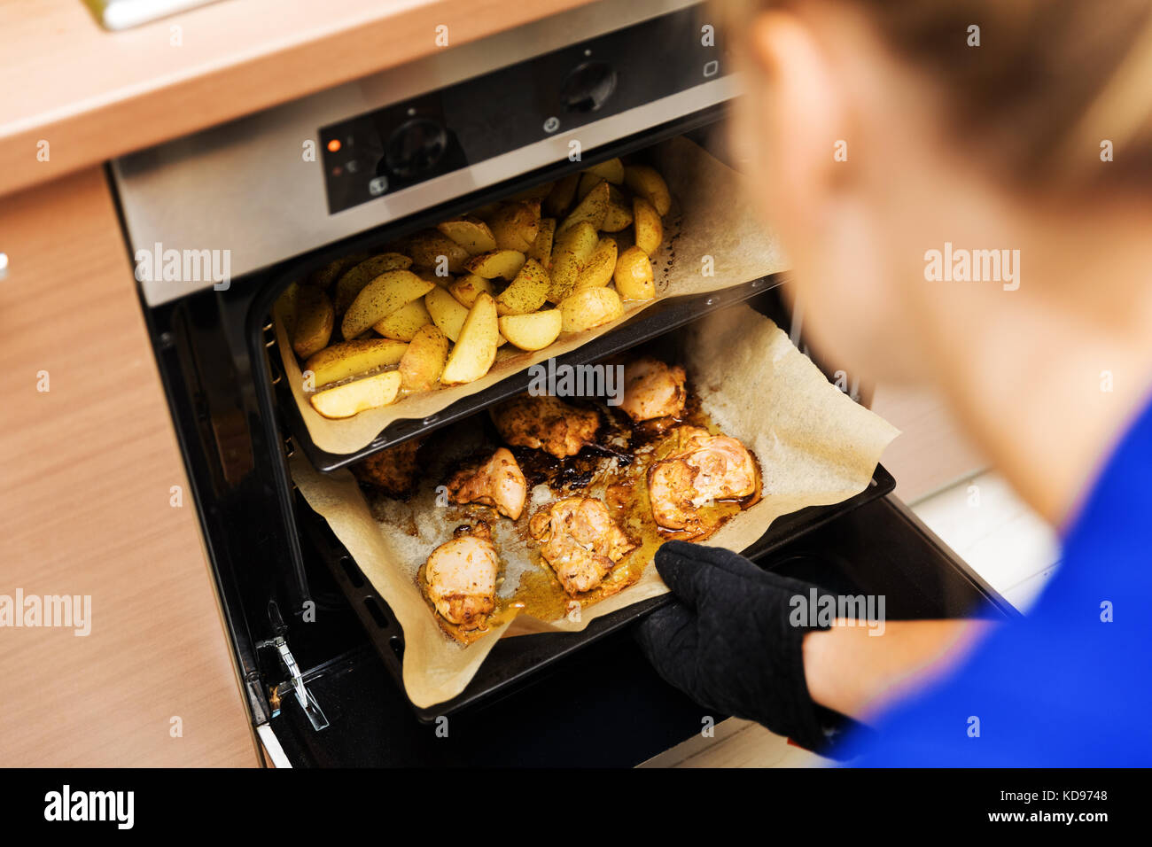 Femme préparant les pommes de terre et de viande de poulet au four à la maison cuisine Banque D'Images