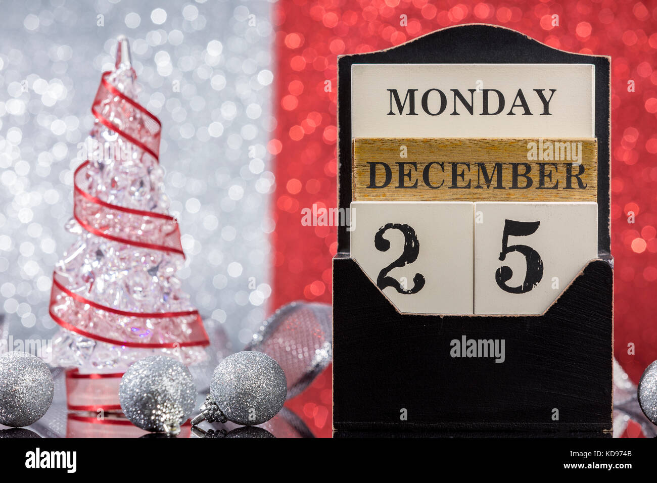 Ornements de Noël Calendrier en bois et l'arbre de Noël réflexion sur table en verre rouge sur un fond argenté Banque D'Images