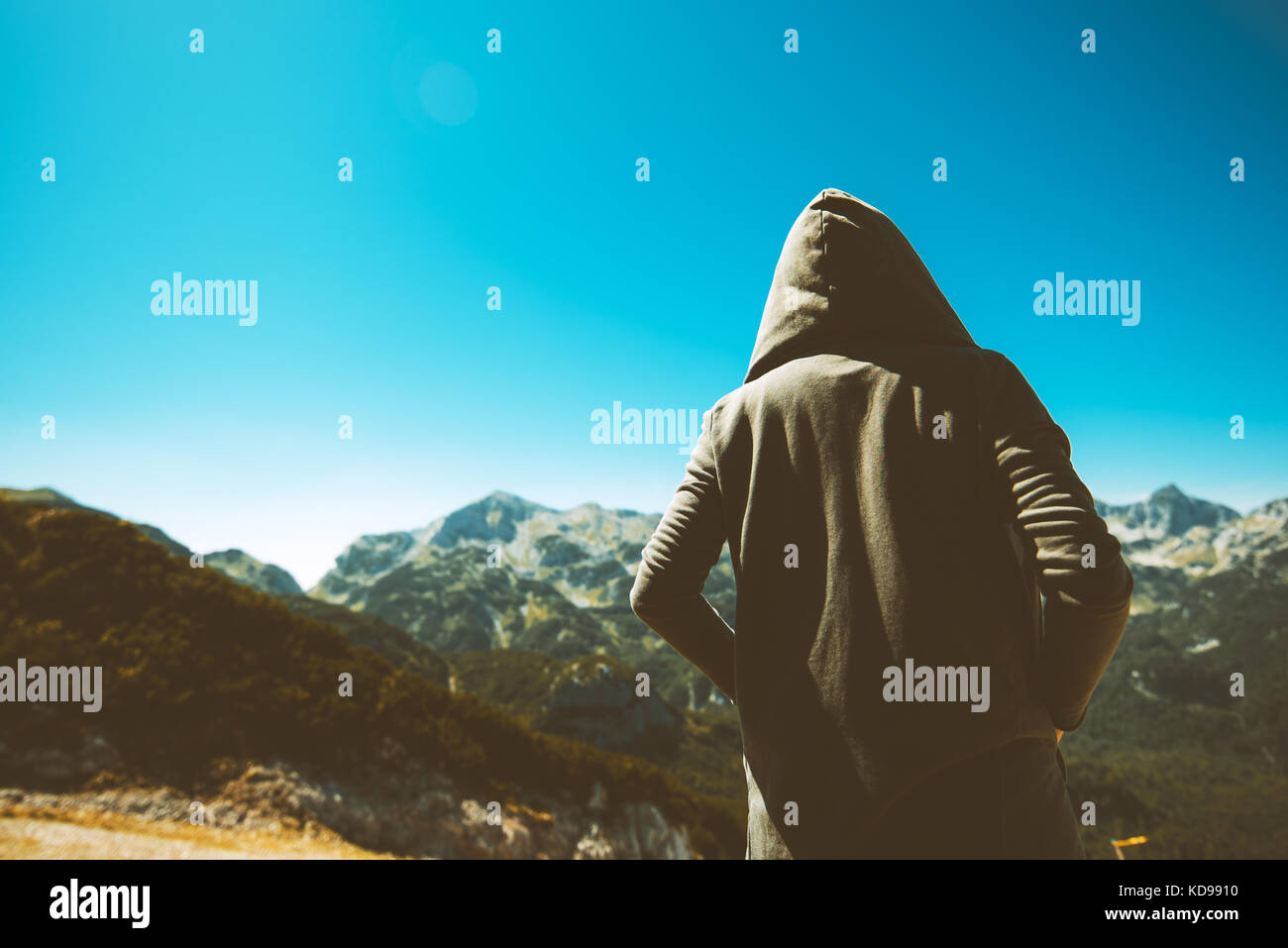 Méconnaissable femme personne debout à la haute montagne vue. young adult woman wearing hoodie à distance à l'horizon sur les tons. Banque D'Images