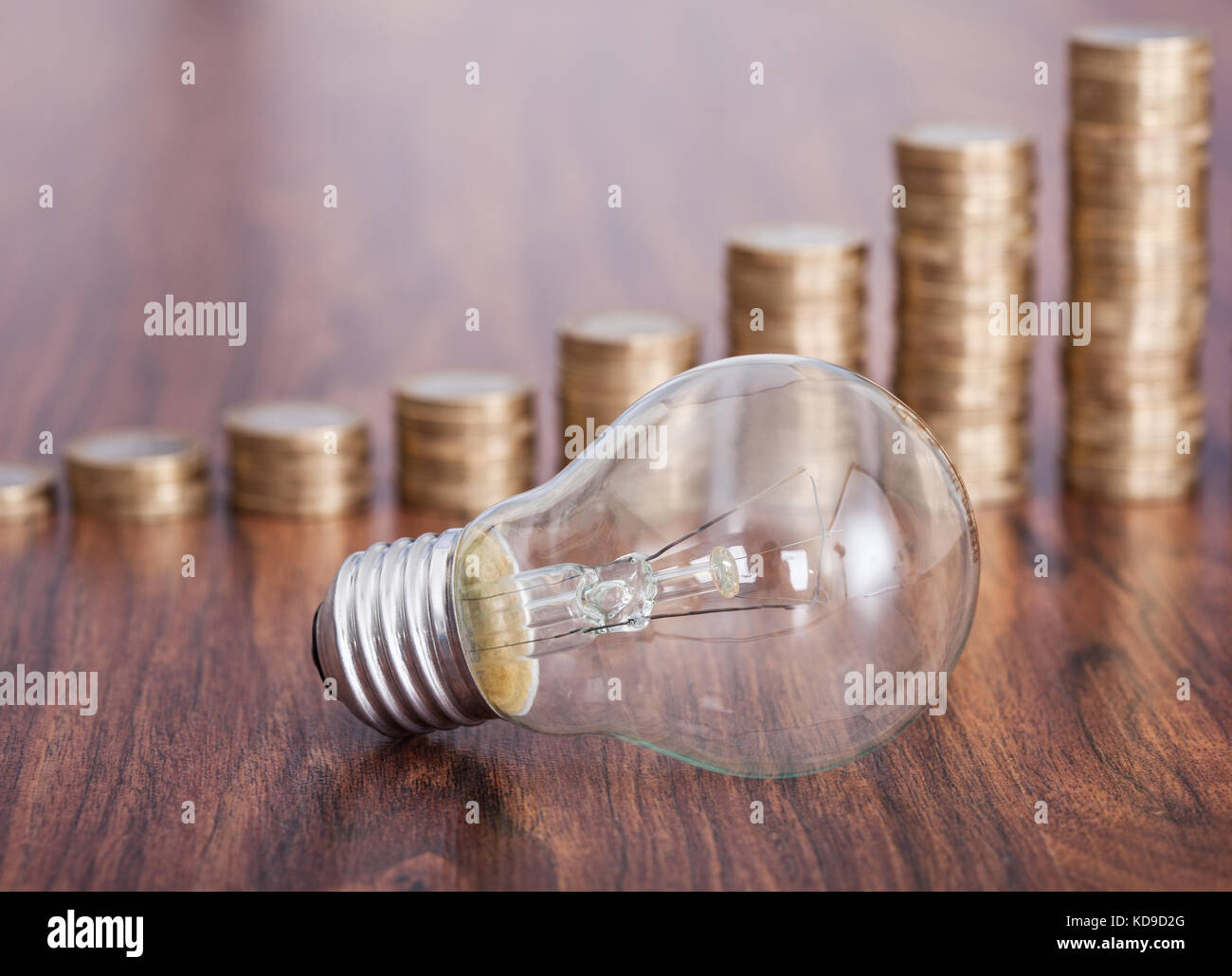 Ampoule avec pile de pièces placées sur la table Banque D'Images