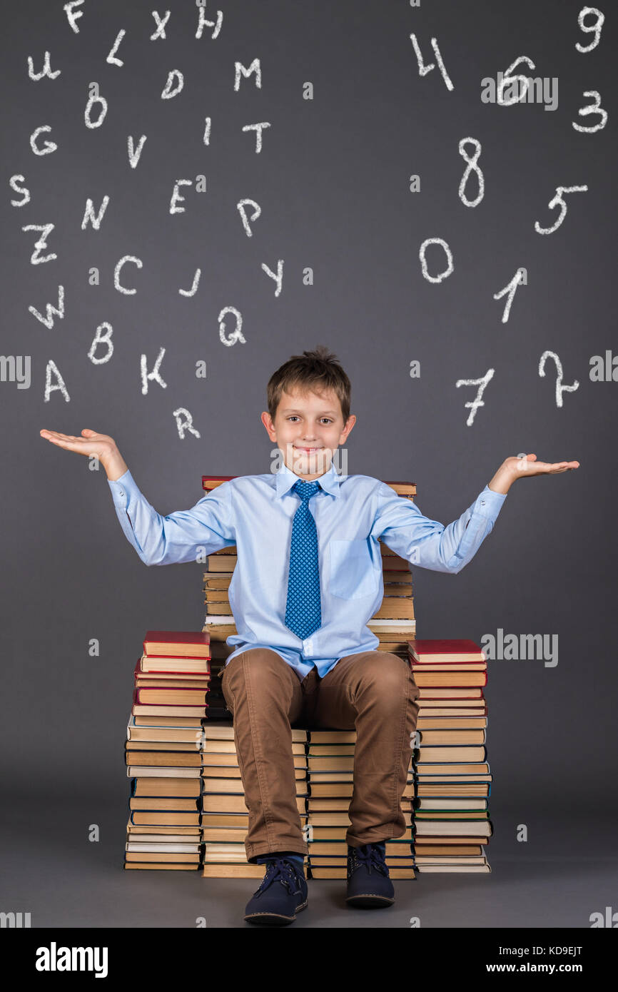 Concept de l'éducation. smiling boy élève pèse l'importance de lettres et chiffres Banque D'Images