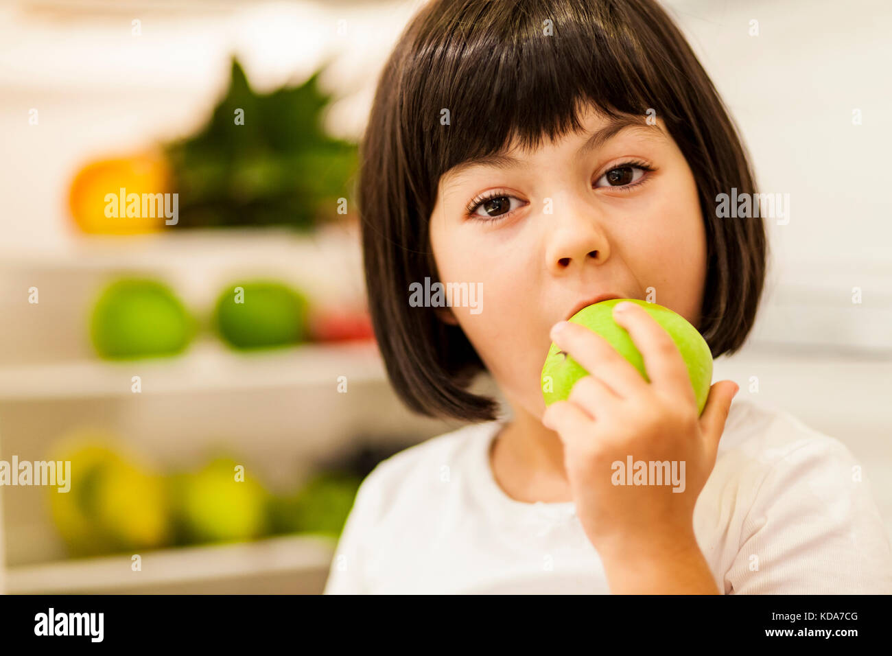 Portrait of cute black hair little girl eating apple Banque D'Images