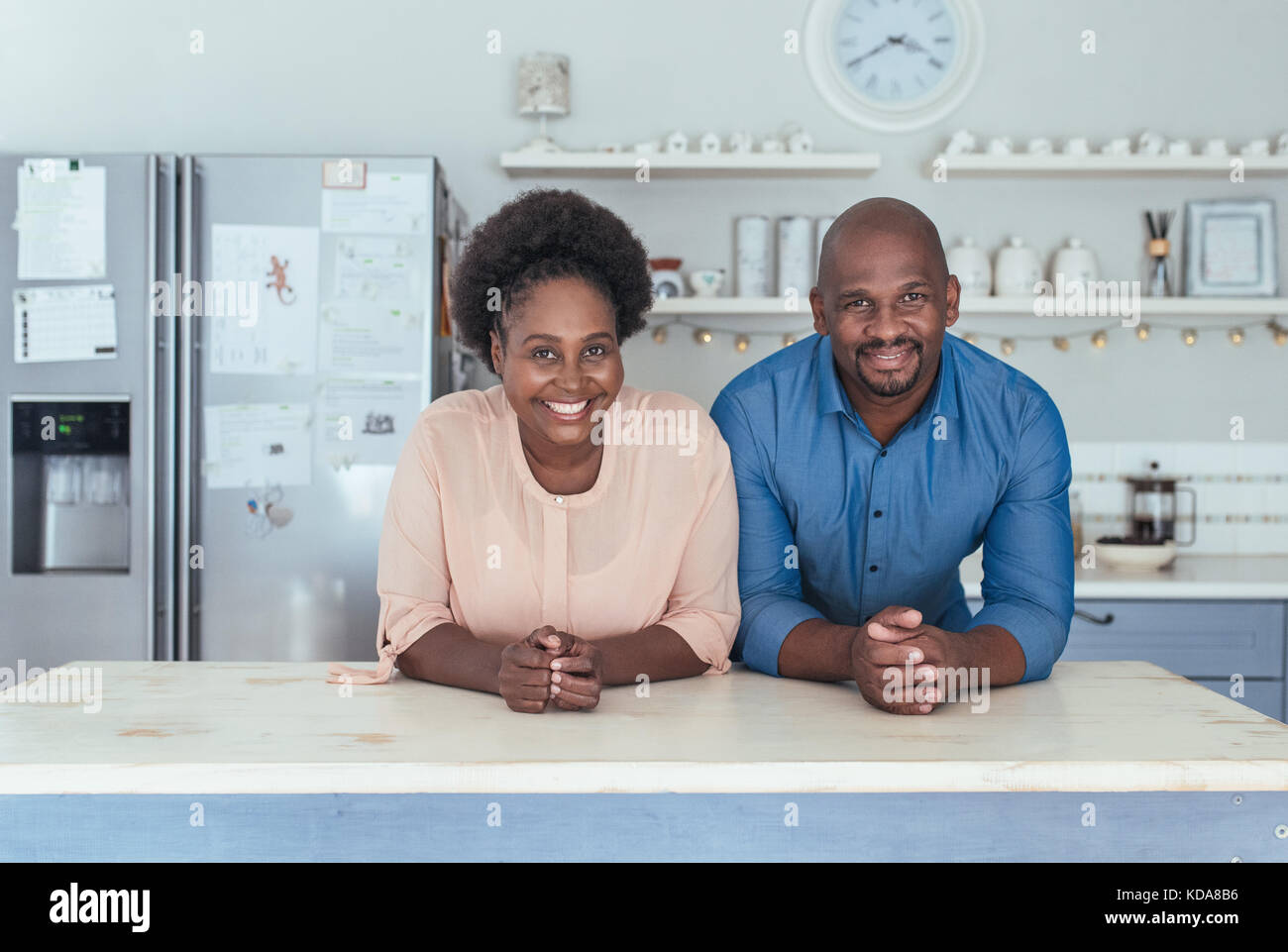 Content african couple s'appuyant sur leur île de cuisine à la maison Banque D'Images