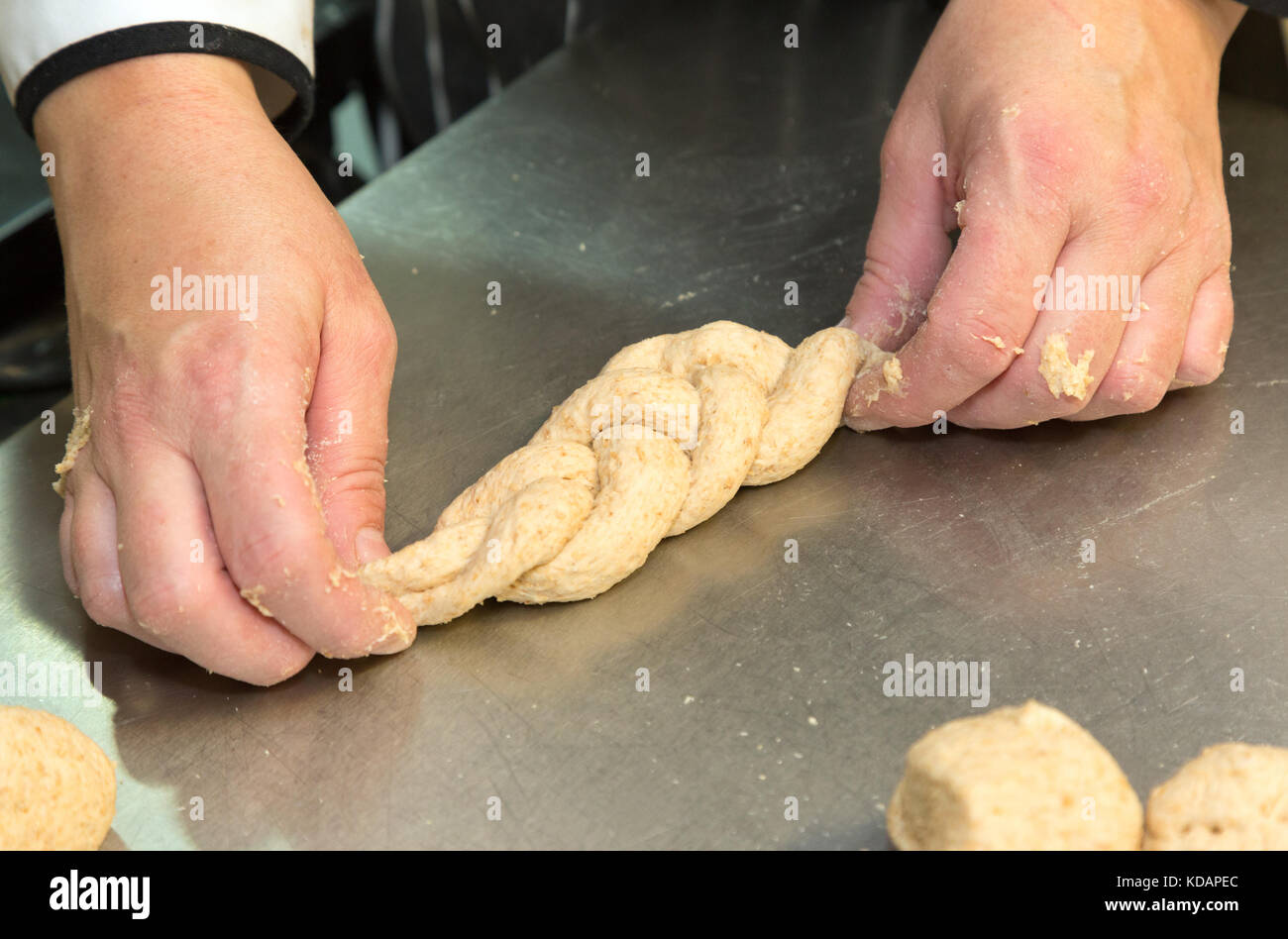 Pain à pâtisserie - façonnage de la pâte pour faire une variété de formes de pain - ici, un petit pain de tresse; UK Banque D'Images