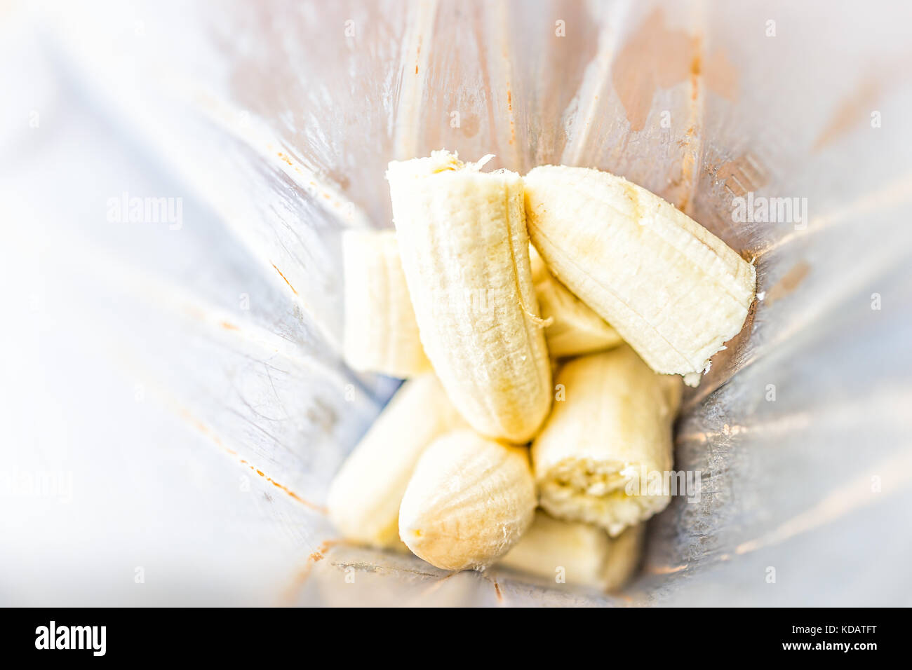 Gros plan macro de bananes fraîches pelées en jaune en plastique contenant du mélangeur pour fruit smoothie fait maison Banque D'Images