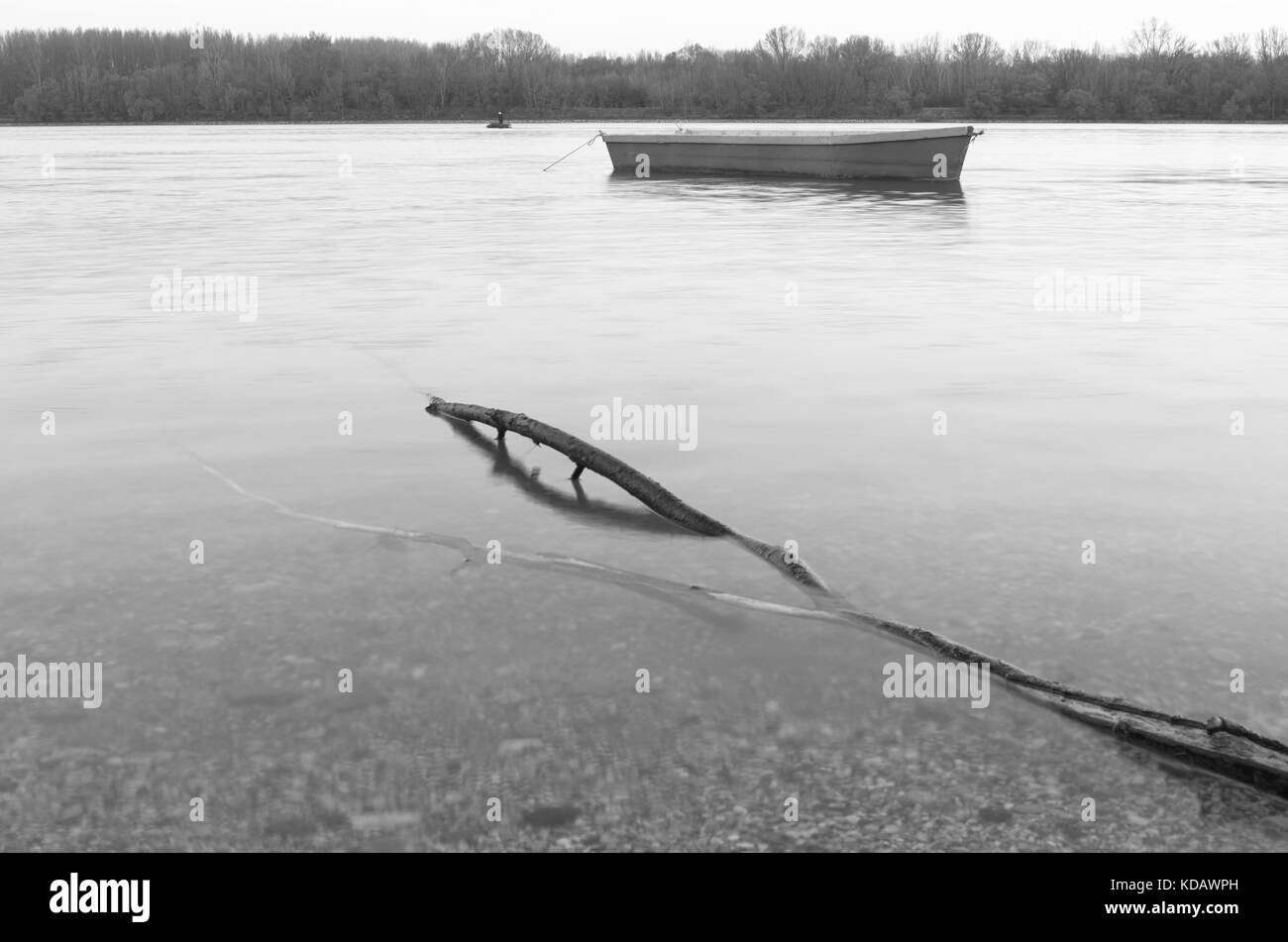 Driftwood et bateau vide dans le calme de l'eau du Danube Banque D'Images