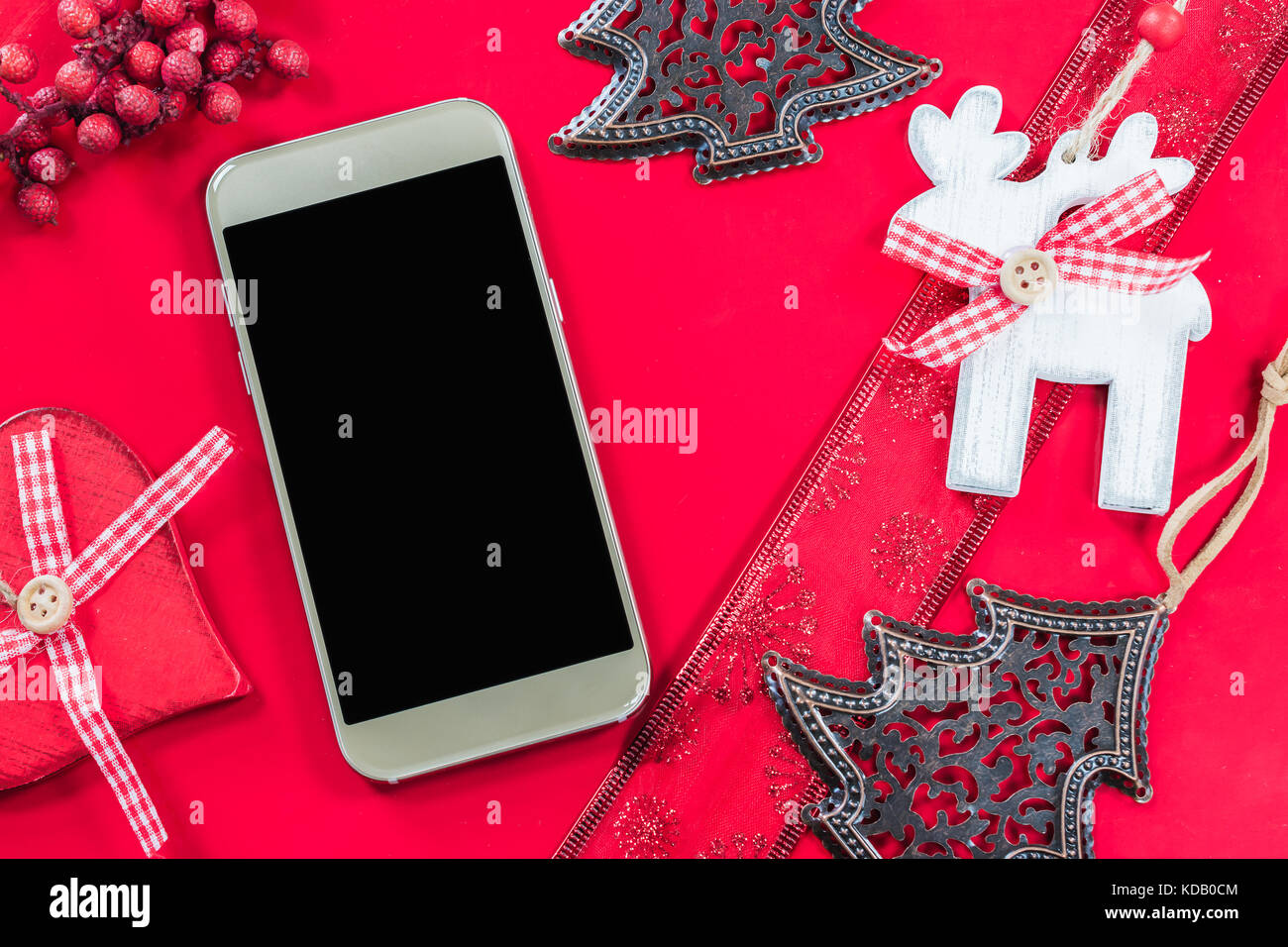 Smart phone et décoration de Noël sur fond rouge. Banque D'Images