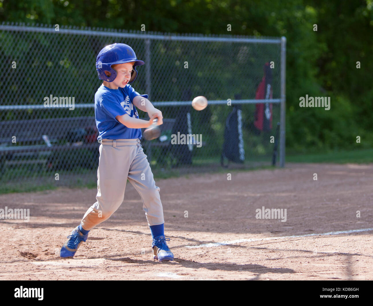 Garçon hitting ball tout en jouant au baseball dans un uniforme bleu Banque D'Images