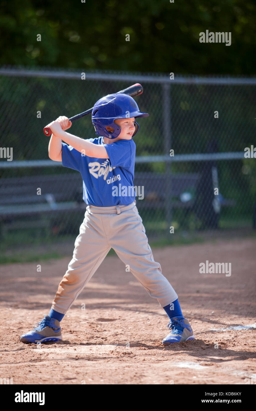 Garçon hitting ball tout en jouant au baseball dans un uniforme bleu Banque D'Images