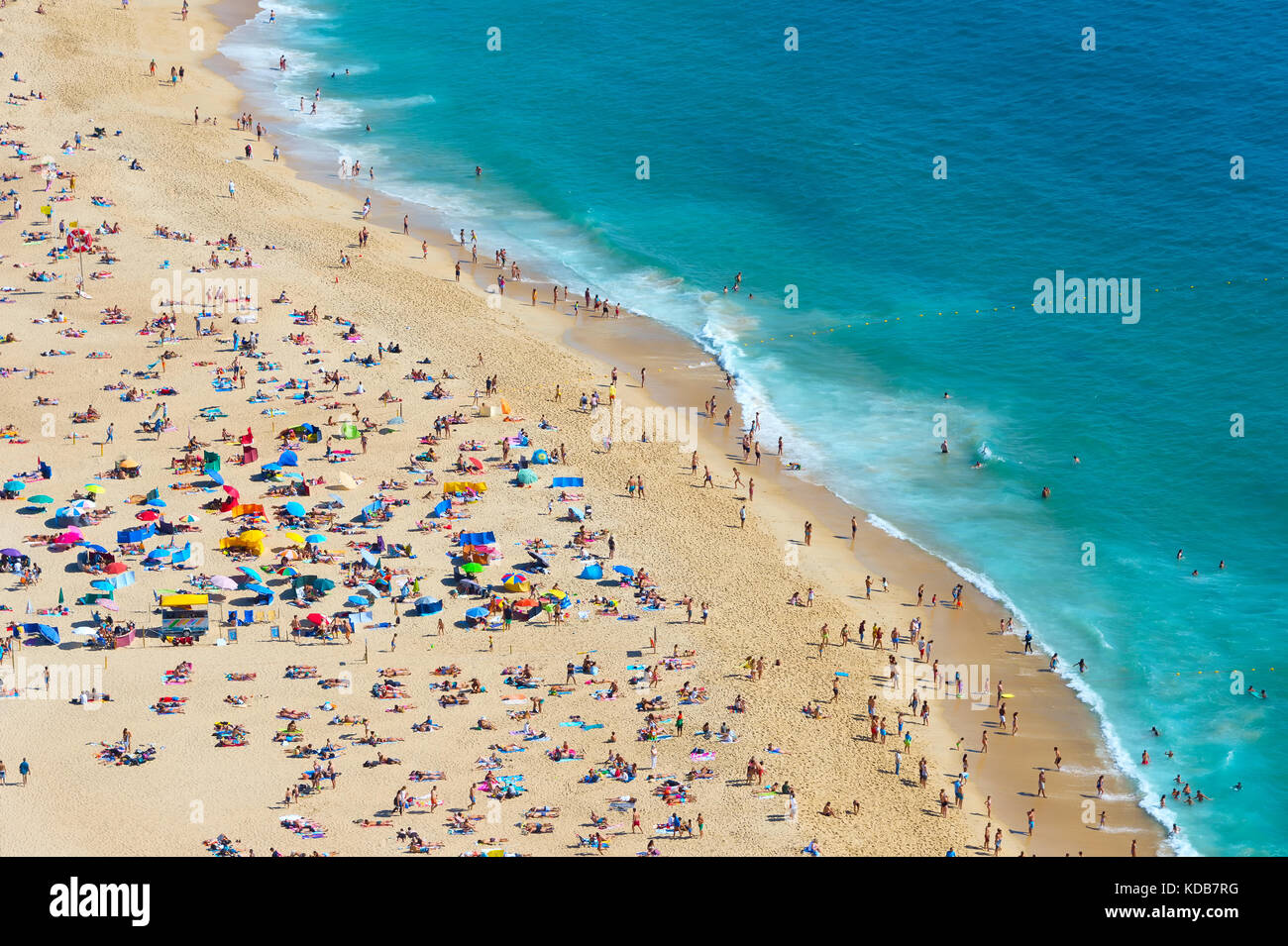 Les gens s'amusant sur la plage sur l'océan dans un bel été ensoleillé jour. Nazare, Portugal Banque D'Images