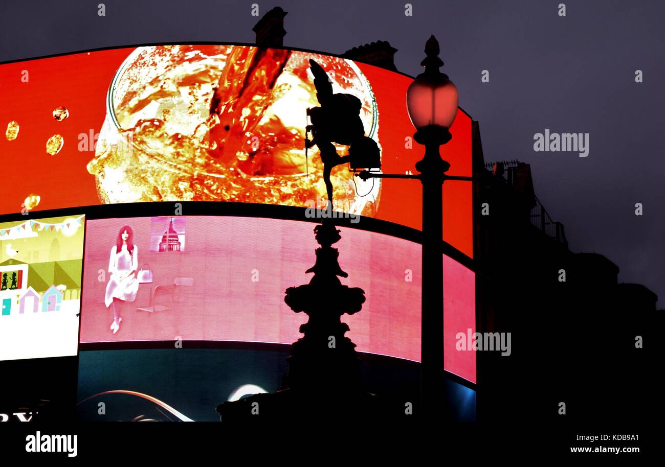 Commercial / Marketing / numérique des écrans publicitaires allume à Piccadilly Circus à Londres, avec une silhouette de l'ange statue d'Anteros sur écran Banque D'Images