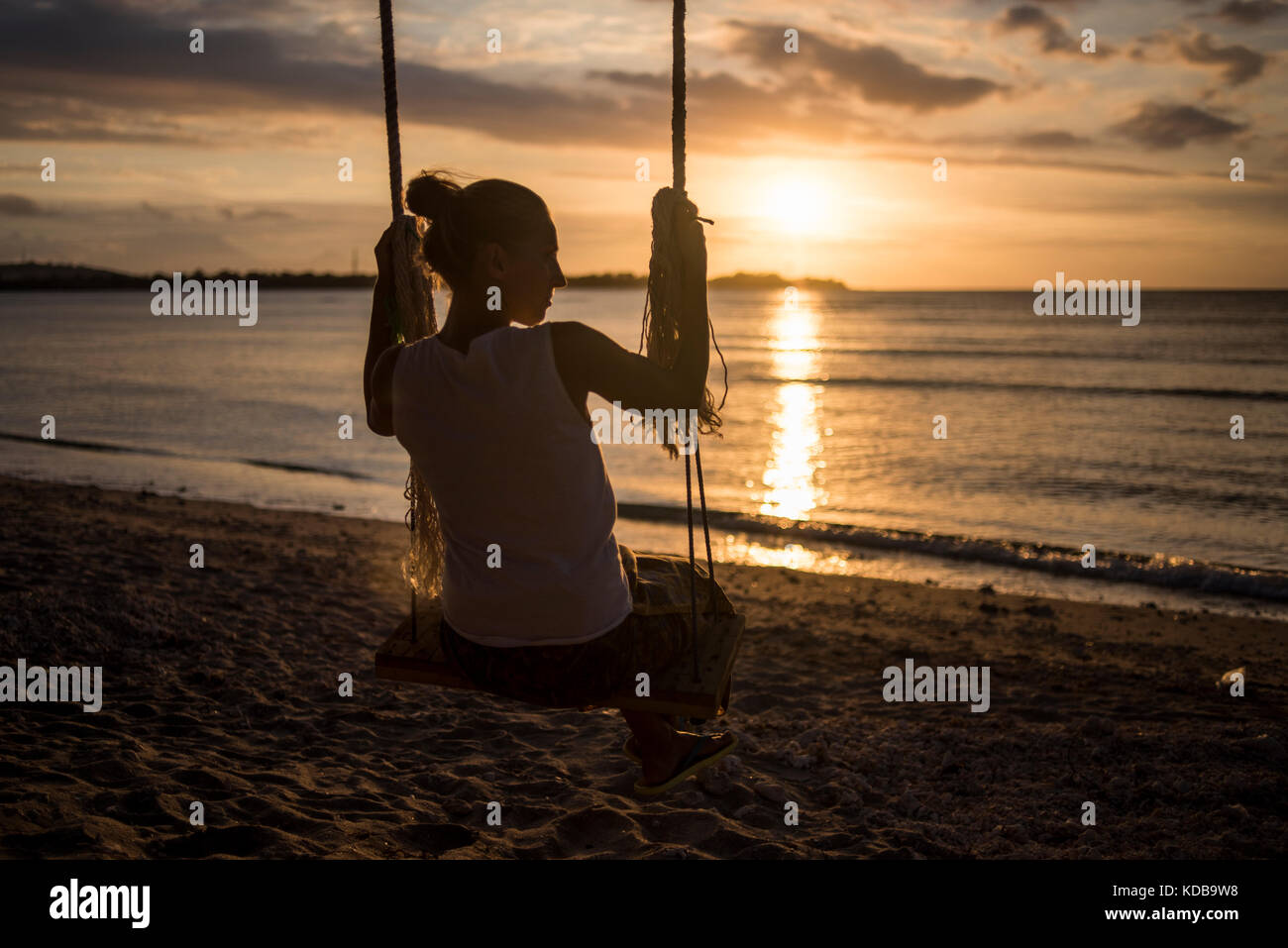 Une silhouette d'une jeune femme sur une balançoire dans un plage de Gili Air, Gili Trawangan, Indonésie. Banque D'Images