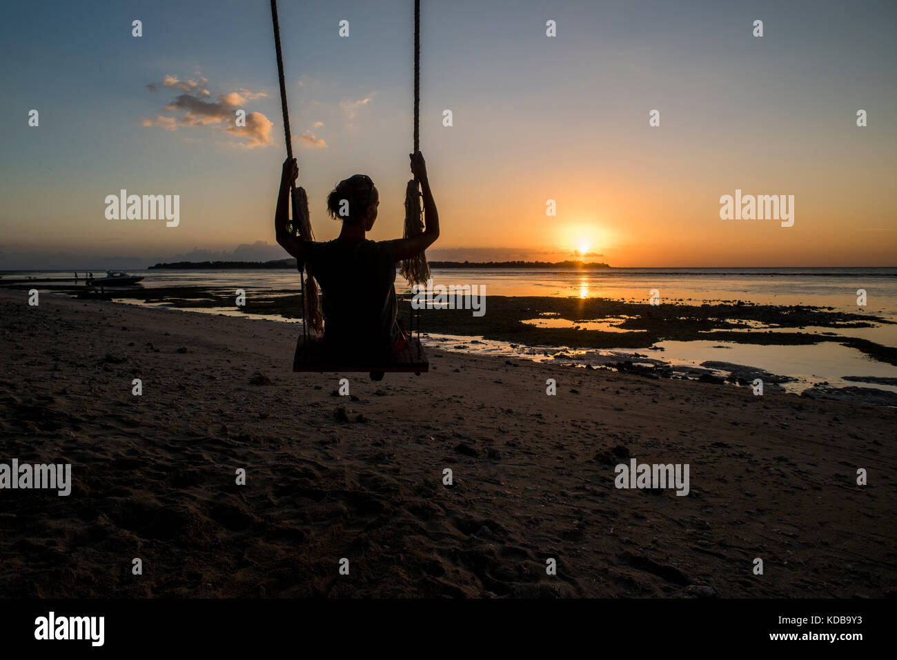 Une silhouette d'une jeune femme sur une balançoire dans un plage de Gili Air, Gili Trawangan, Indonésie. Banque D'Images