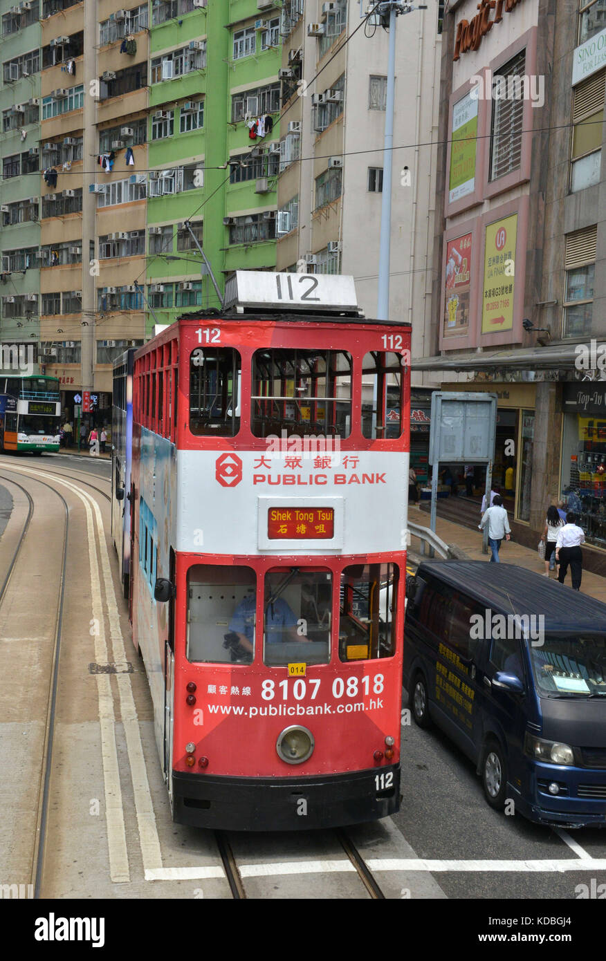 En bas des bâtiments, double-decker colorés tram appartenant à Hong Kong Tramways avec de grandes annonces sur ses côtés. La banque publique locale *** annonce Banque D'Images