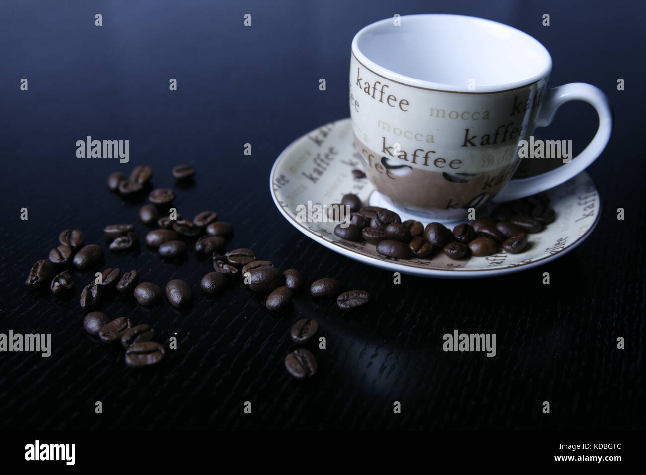 Moccatasse verstreuten kaffeetasse mit Kaffee Bohnen auf schwarzem tisch - Mocca tasse tasse à café avec café en grains éparpillés sur le tableau noir Banque D'Images