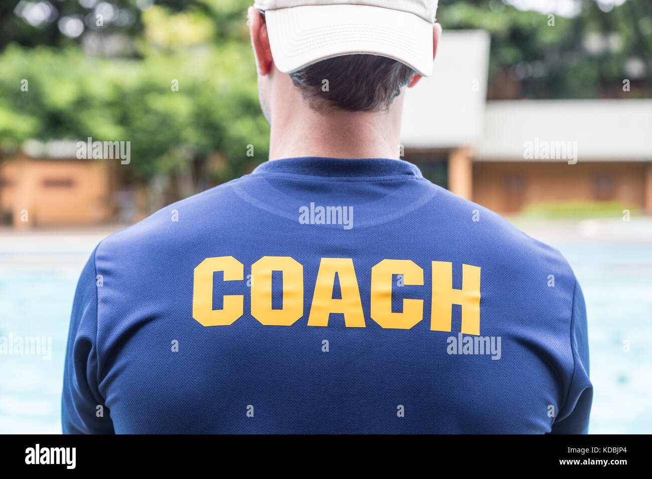 Retour d'un sport coach's blue shirt avec le yellow coach mot écrit dessus ; bon contexte pour le sport ou l'entraînement thème Banque D'Images