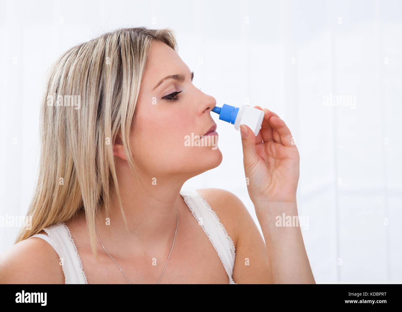 Close up of a woman using nasal spray isolé sur fond blanc Banque D'Images