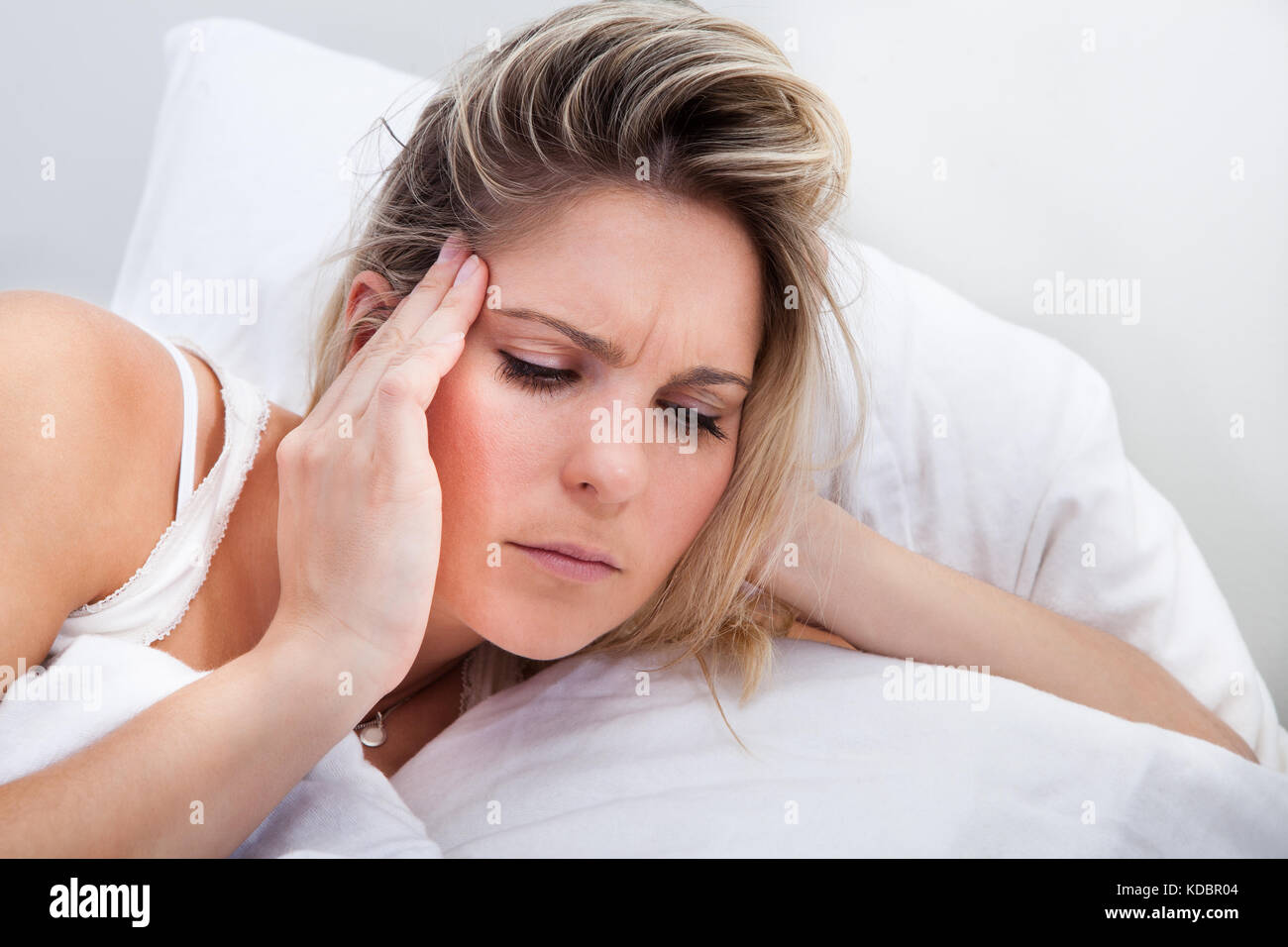 Portrait de femme avec des maux de lying on bed Banque D'Images