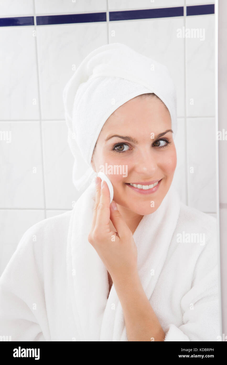 Jeune femme essuyant le visage avec un coton Banque D'Images