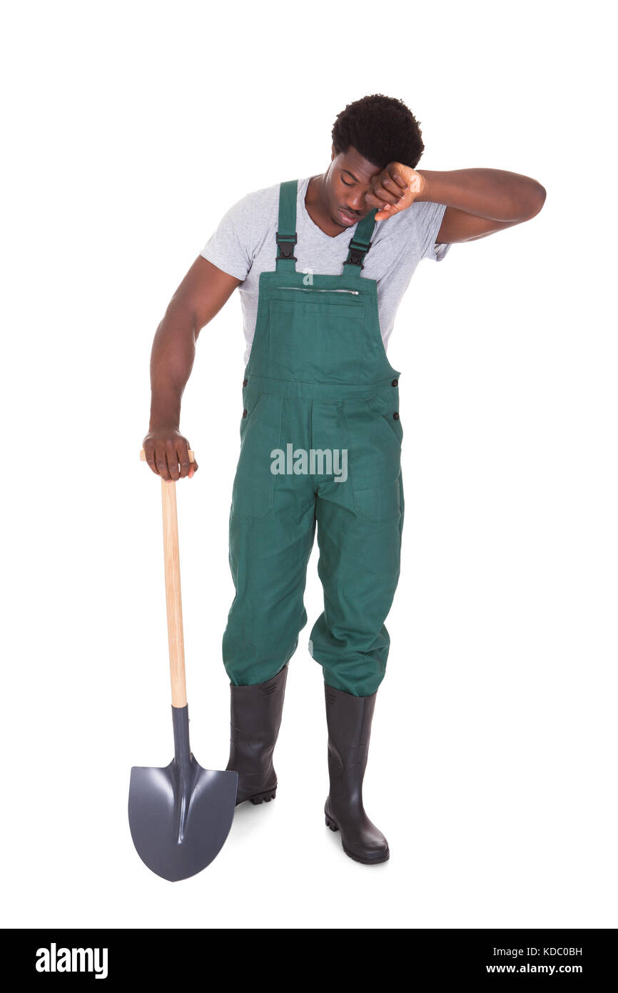 Jardinier homme fatigué Holding Shovel sur fond blanc Banque D'Images