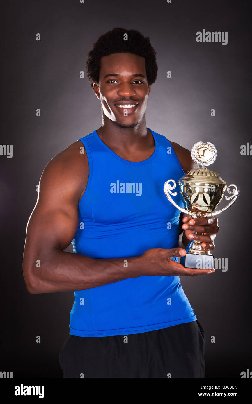 Happy African Man Holding Trophy sur fond noir Banque D'Images